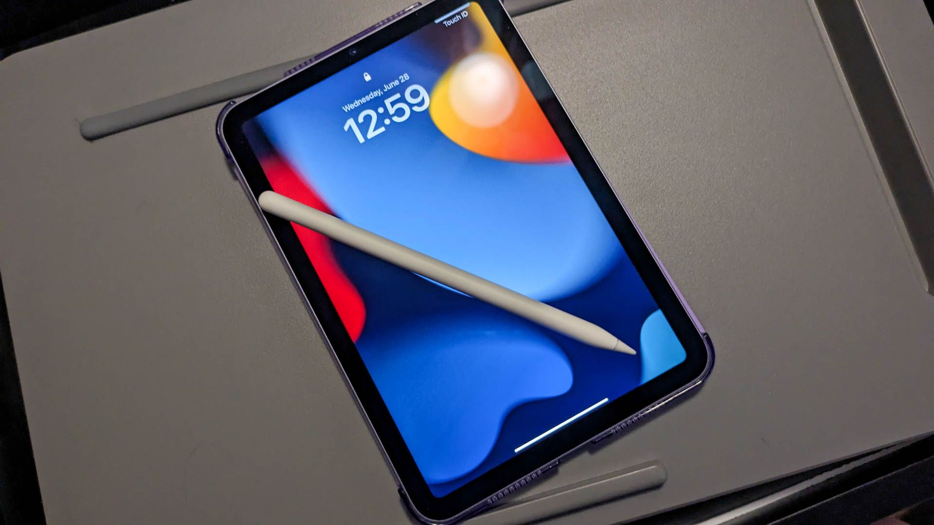 An iPad Mini with an Apple Pencil on a lap desk