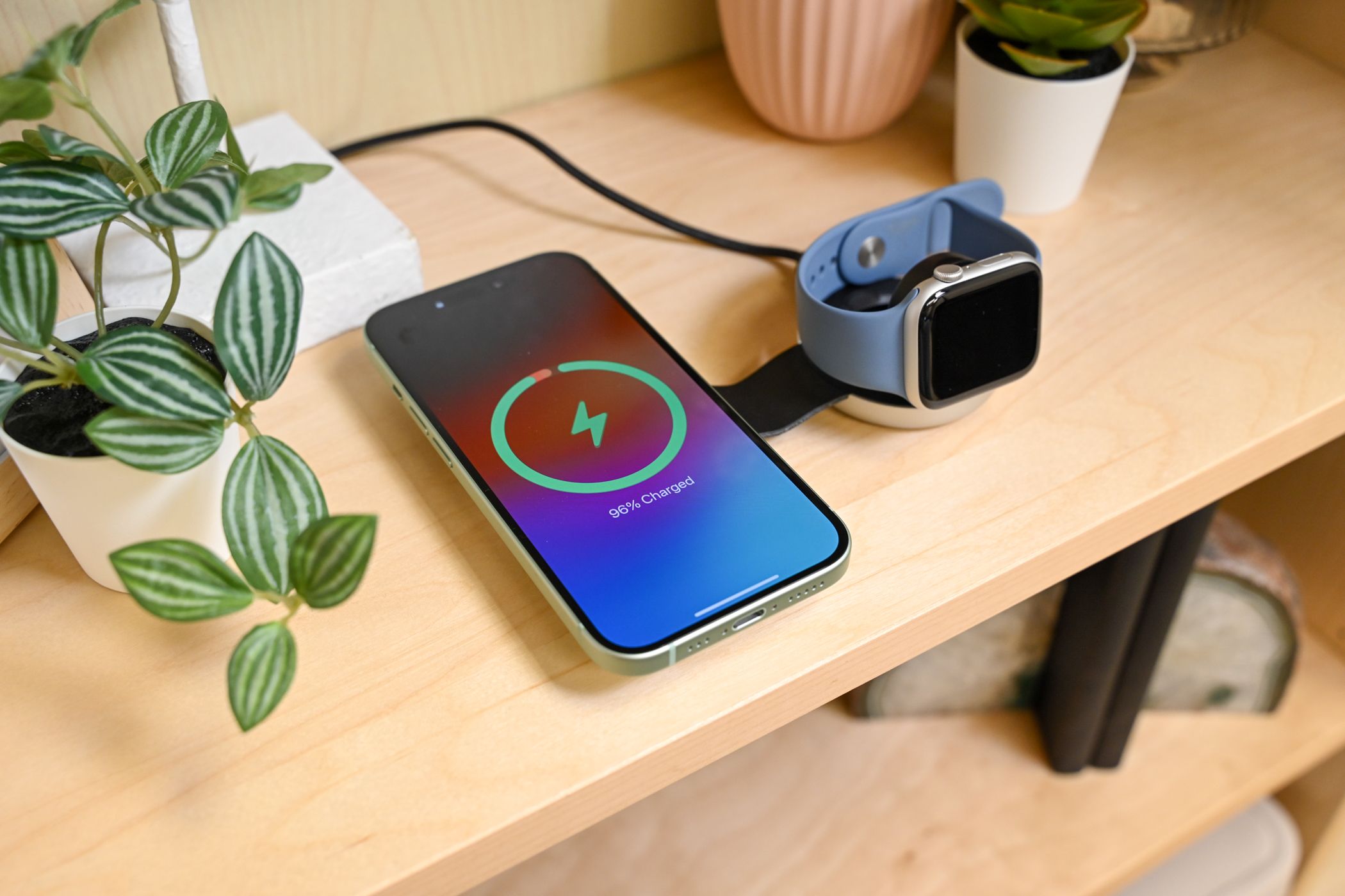 iPhone 15 and an Apple Watch on a wireless charger.