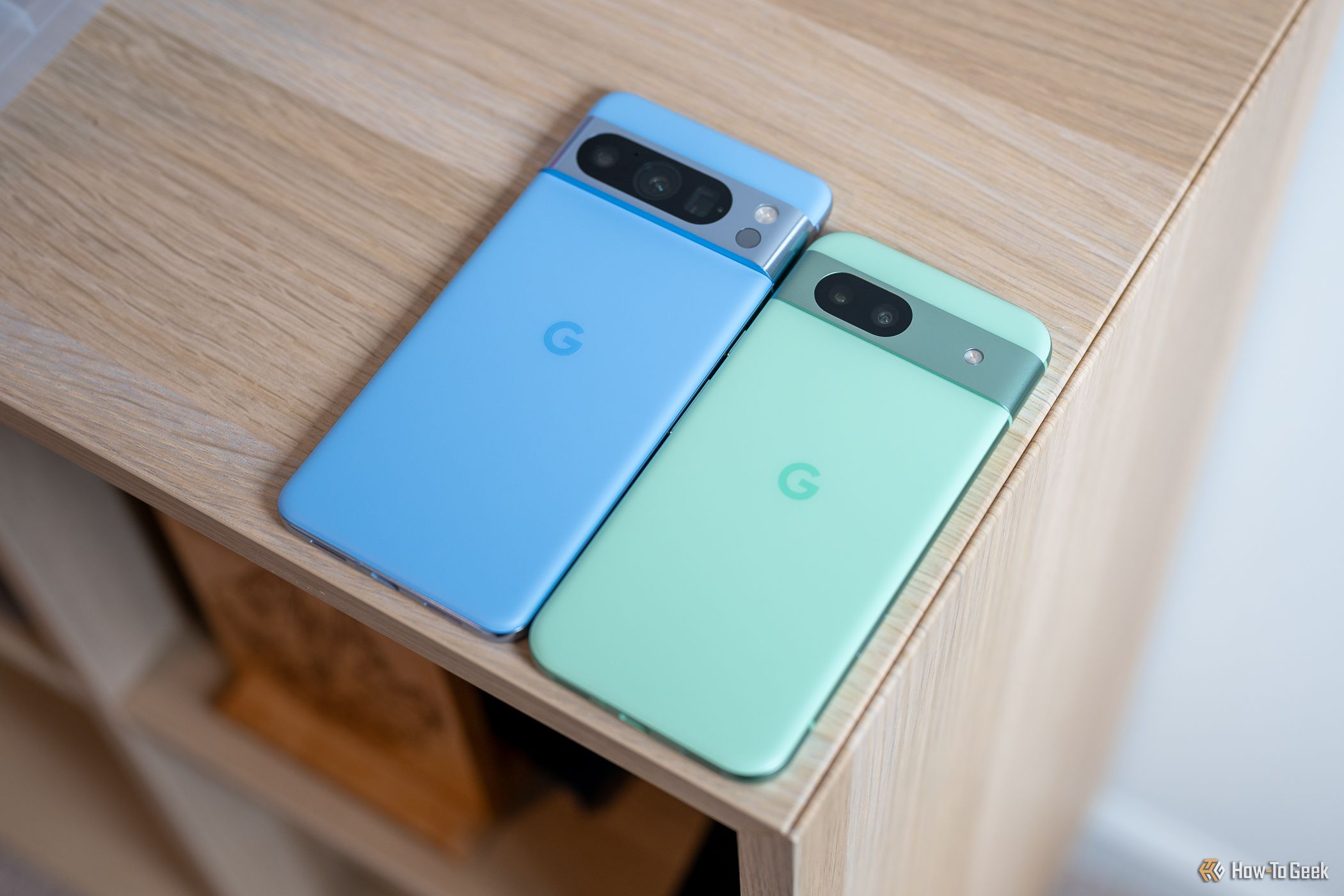 Google Pixel 8a sitting on a table next to a Pixel 8 Pro