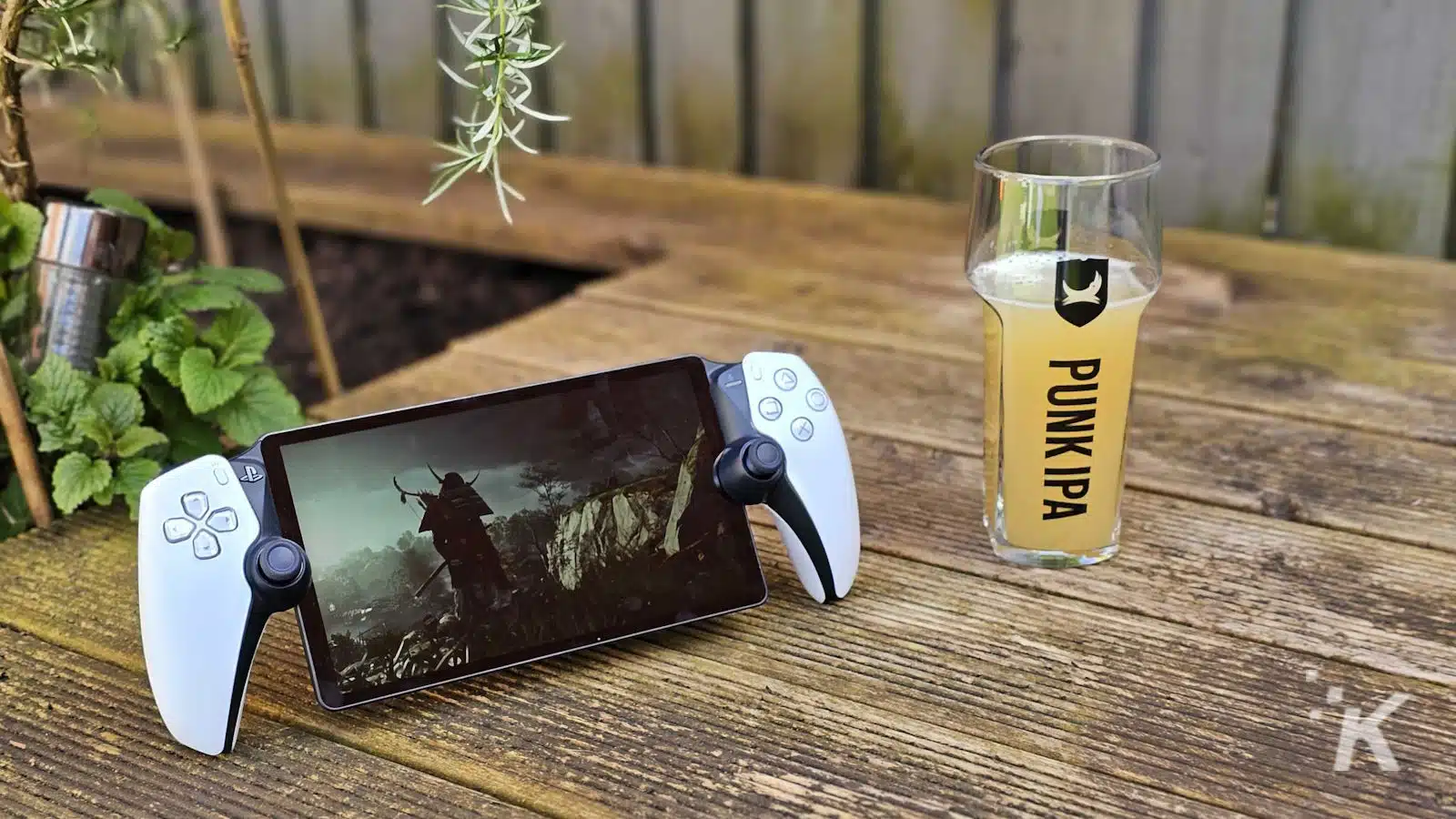 PlayStation Portal device and beer glass on wooden table.