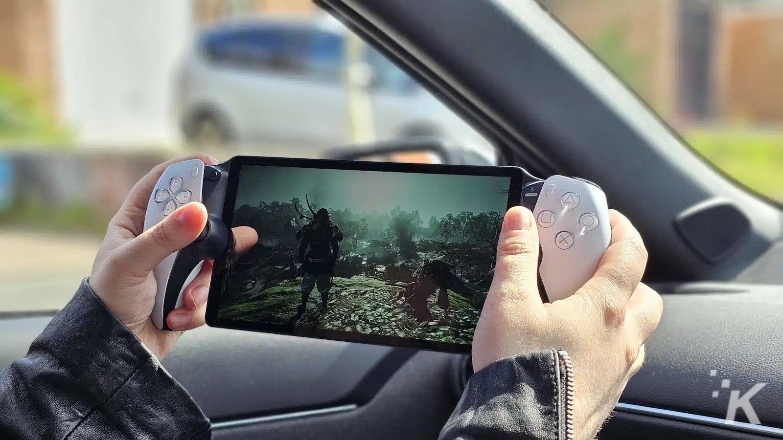 Person playing handheld game console in car.