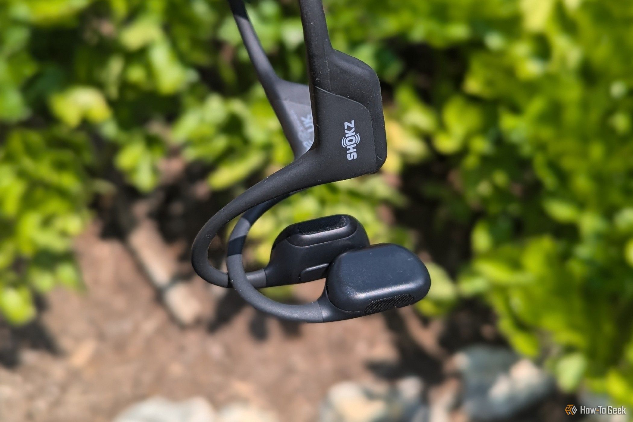 Shokz open-ear headphones with garden in the background