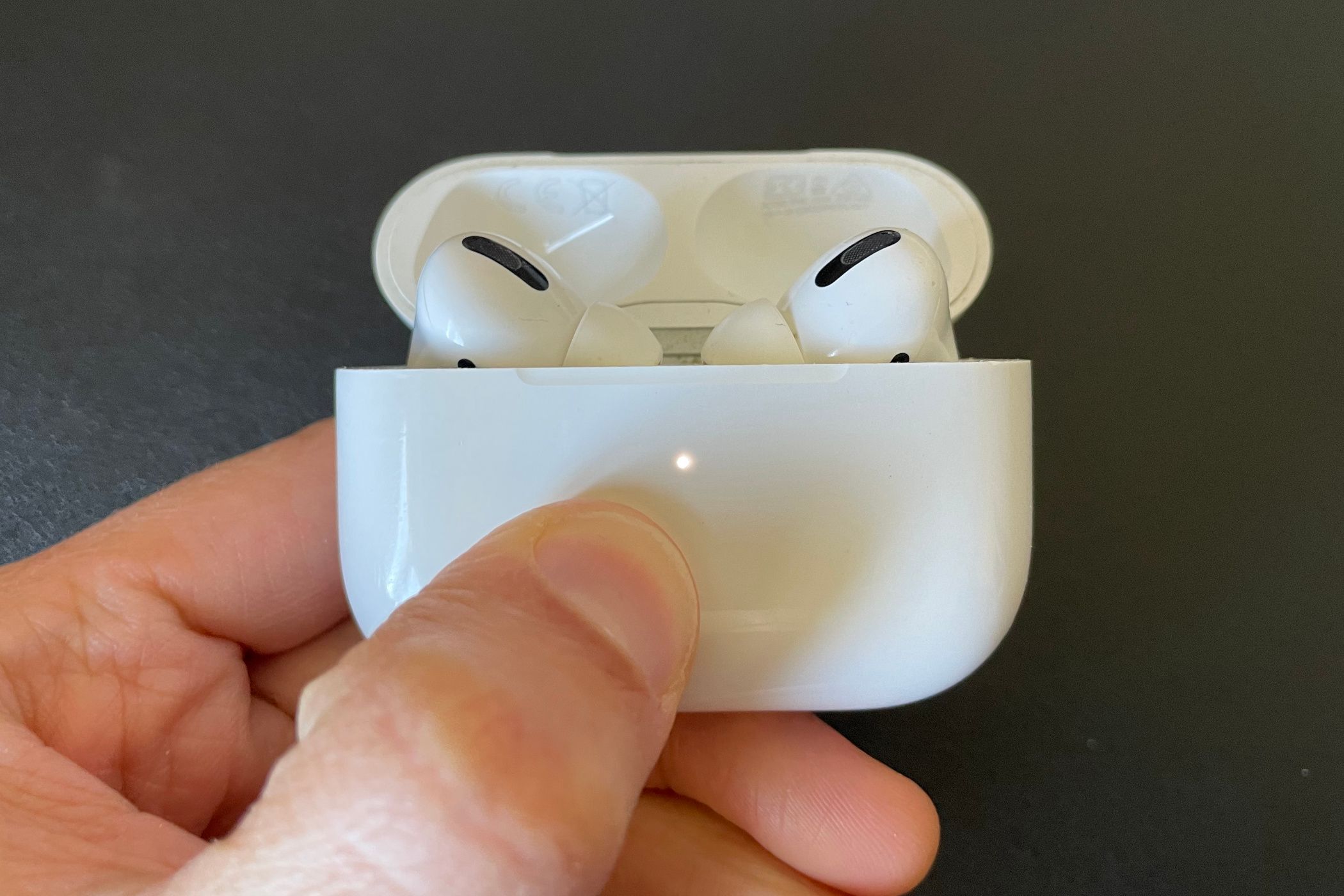 AirPods Pro inside charging case with white status light.