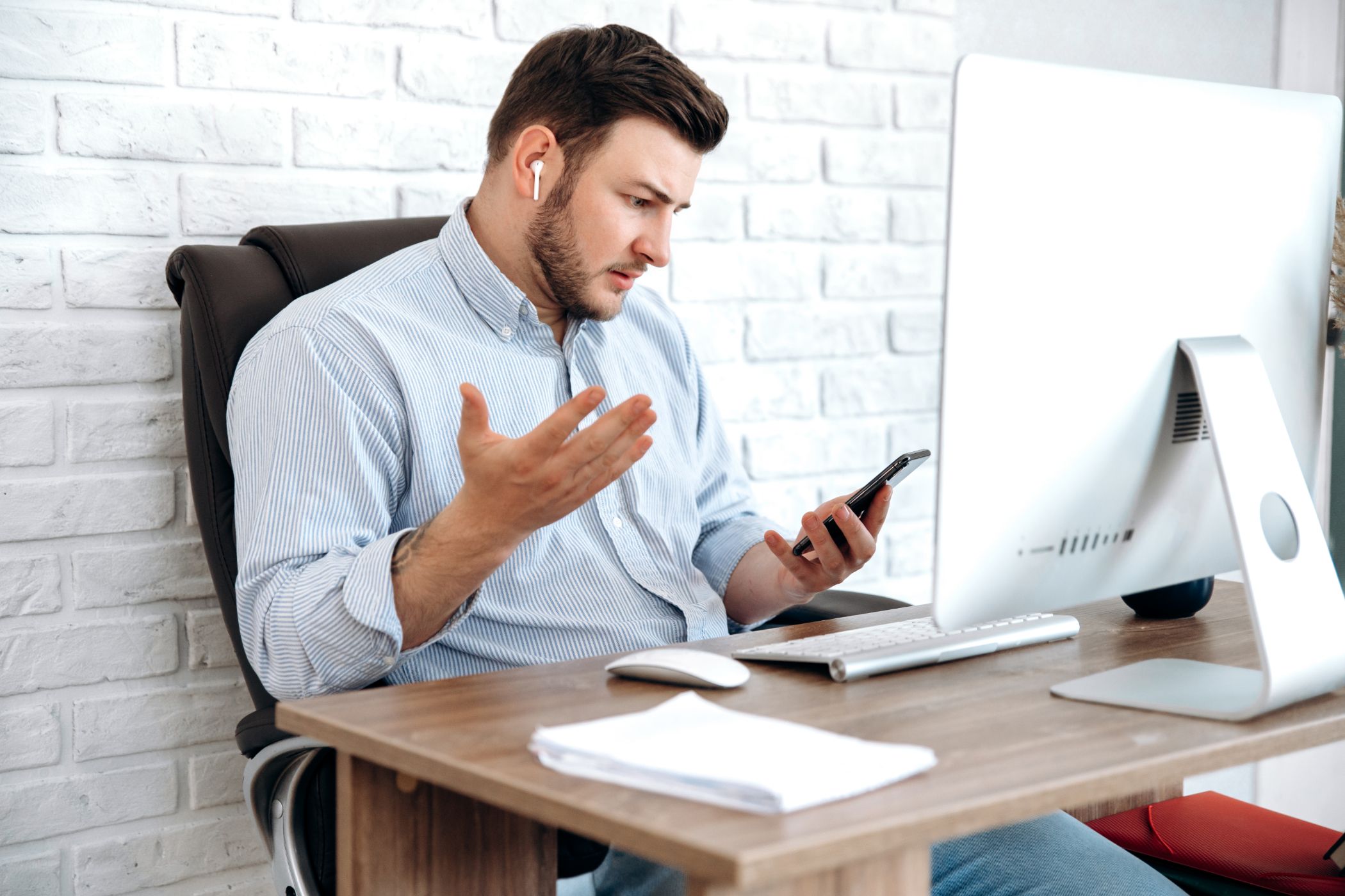 Man using AirPods and looking at his iPhone in surprise