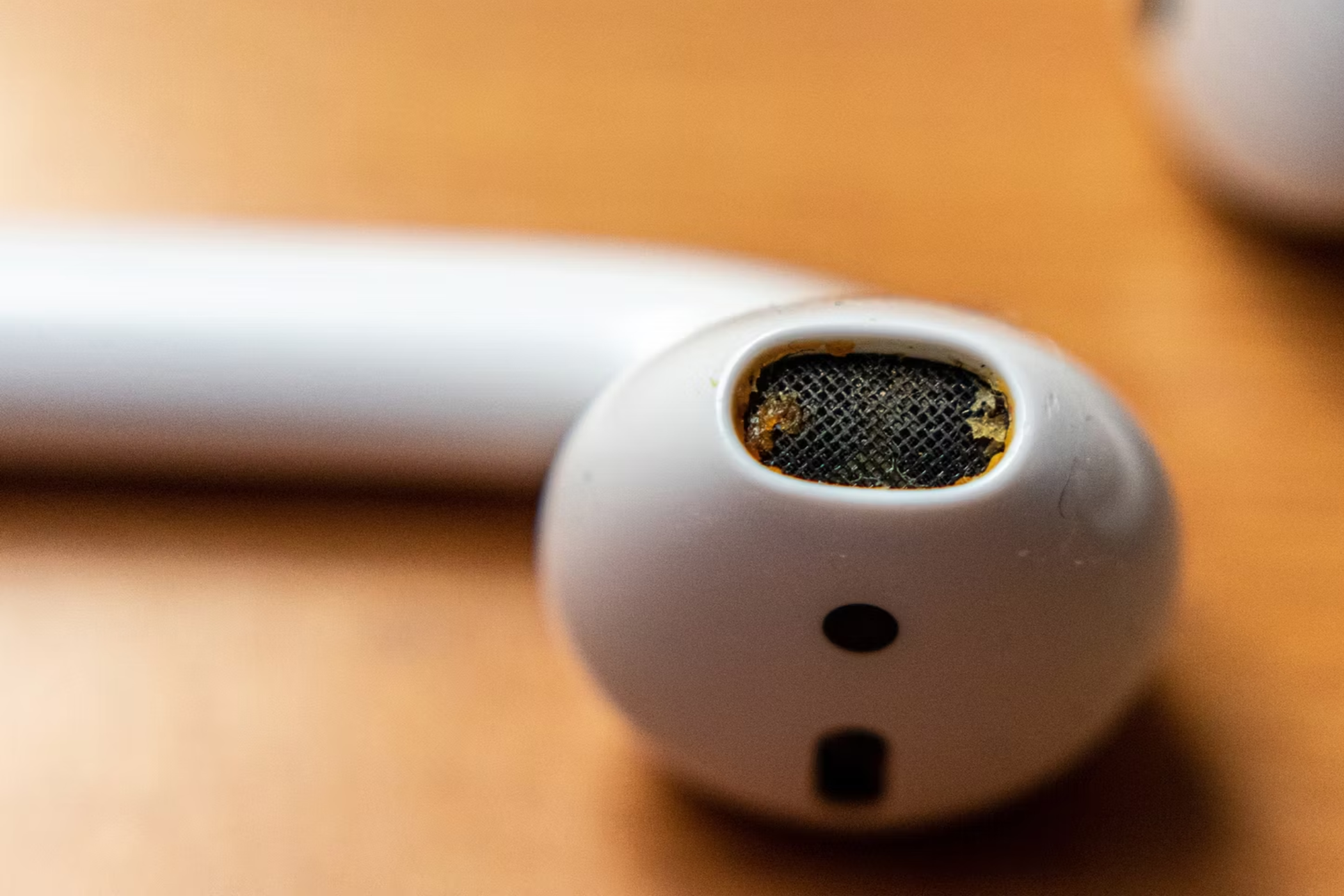 Dirty primary acoustic outlet of Apple AirPods with accumulated earwax, grease and dirt.