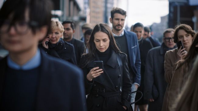 A crowd of people using smartphones on a city street.