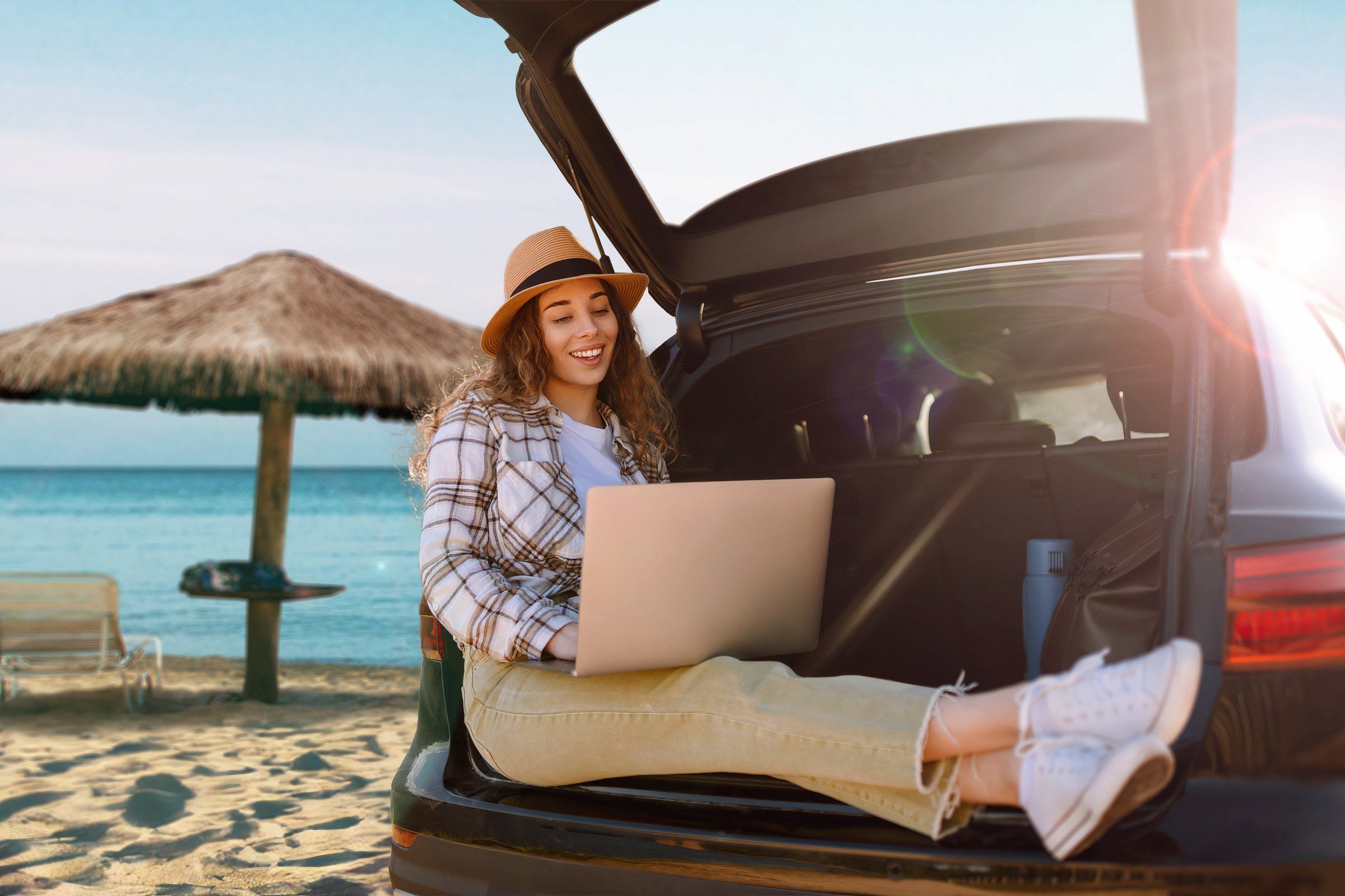 Woman using a laptop in her car at the beach.