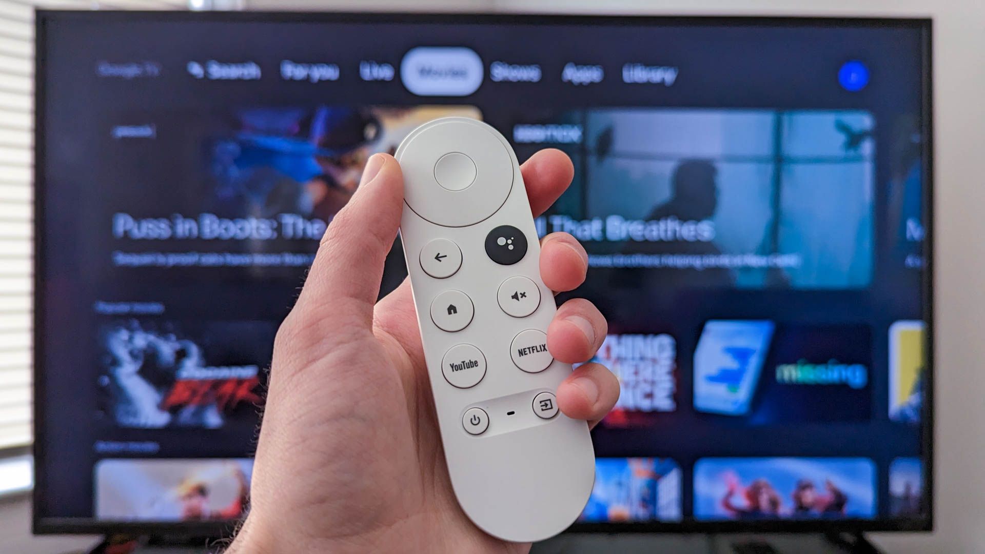 Person holding a Chromecast remote infront of a tv with Google TV open