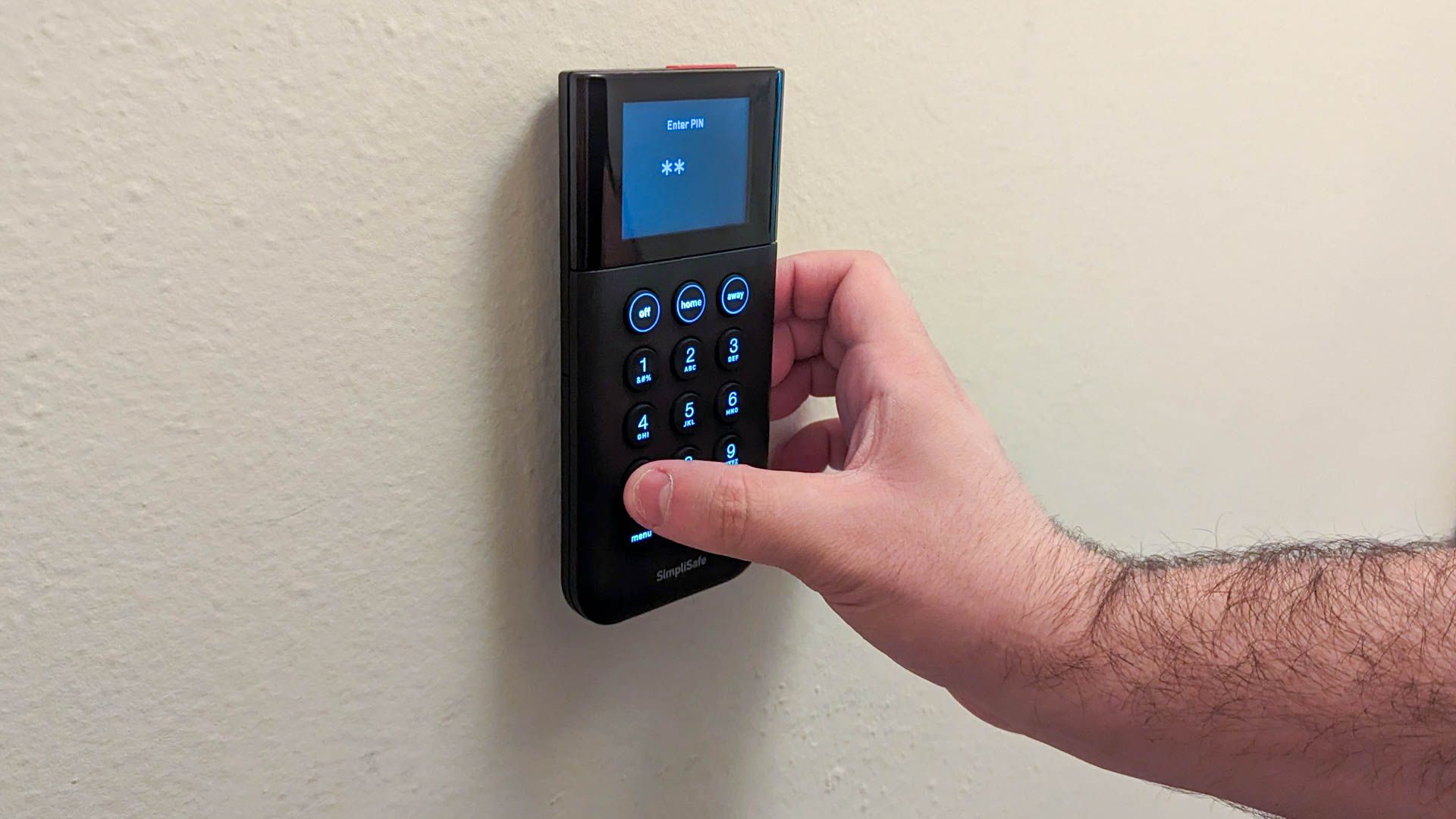 Person disabling a SimpliSafe home security system by typing in a code