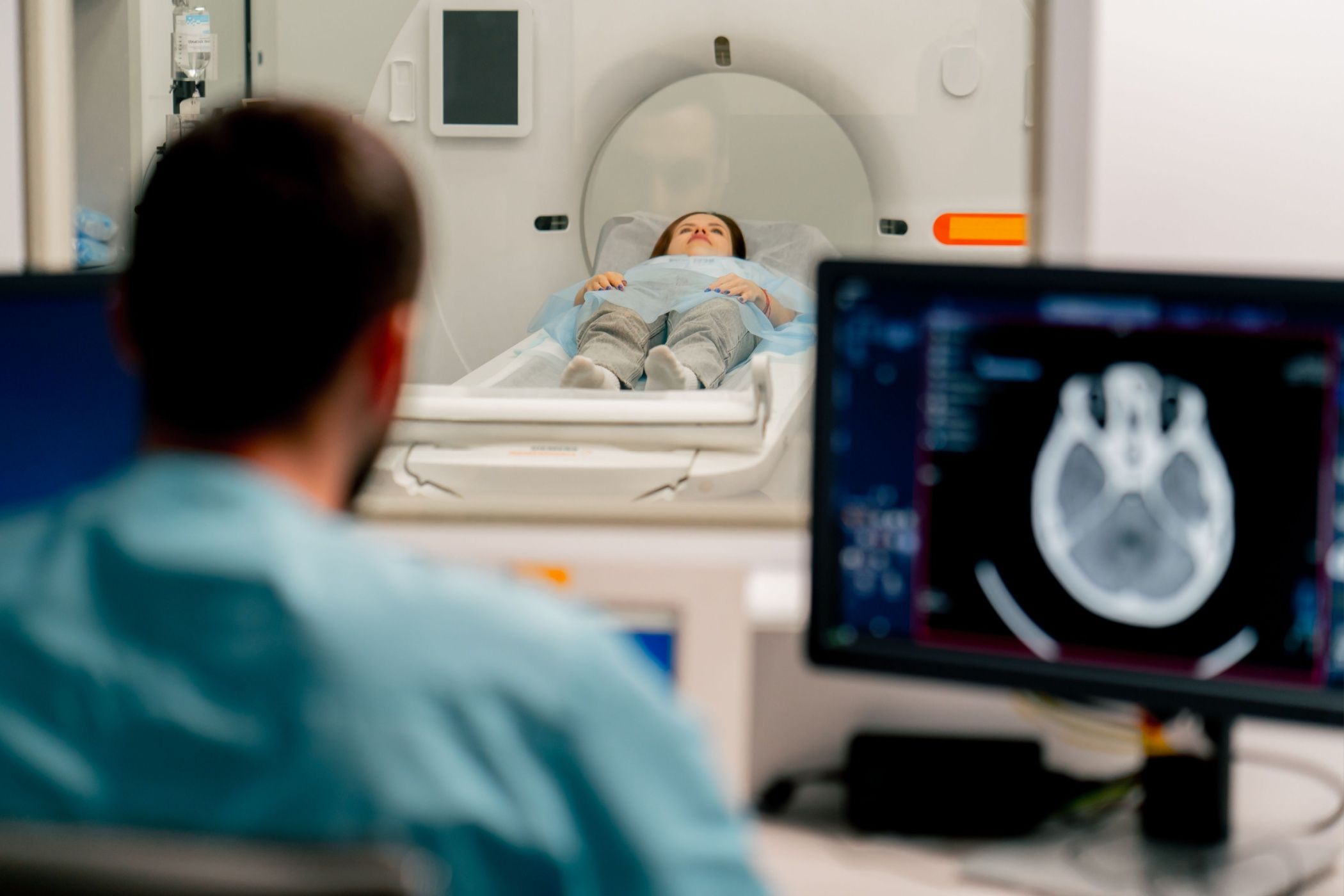 A girl lies on an MRI machine before examining her body and the radiologist gives command to her to prepare for a diagnosis