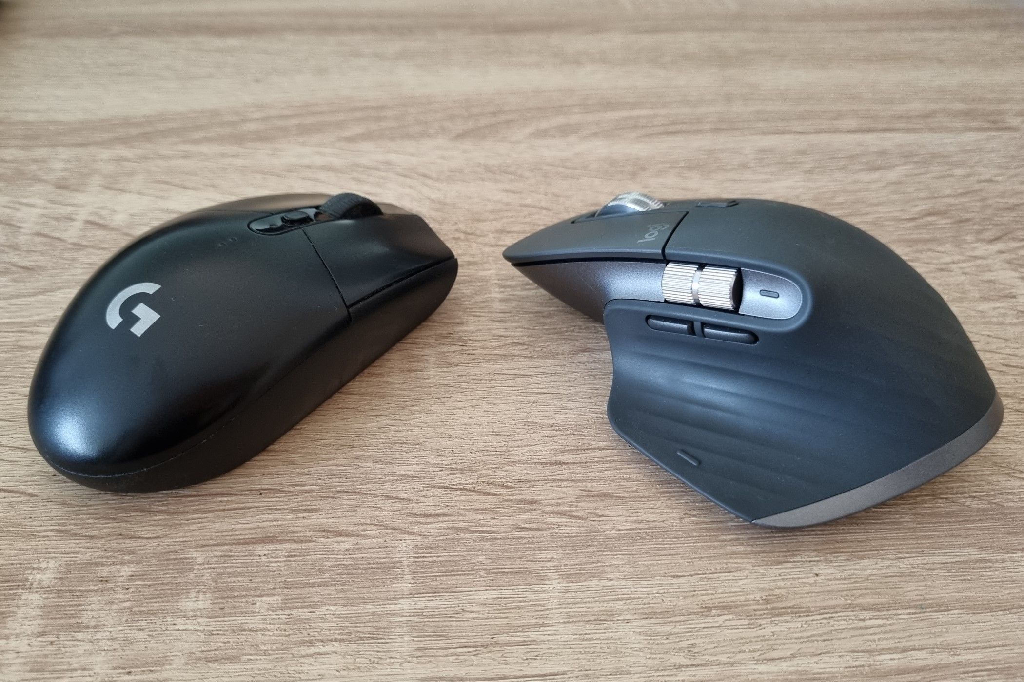 A Logitech G305 and a Logitech MX Master 3S facing against each other.