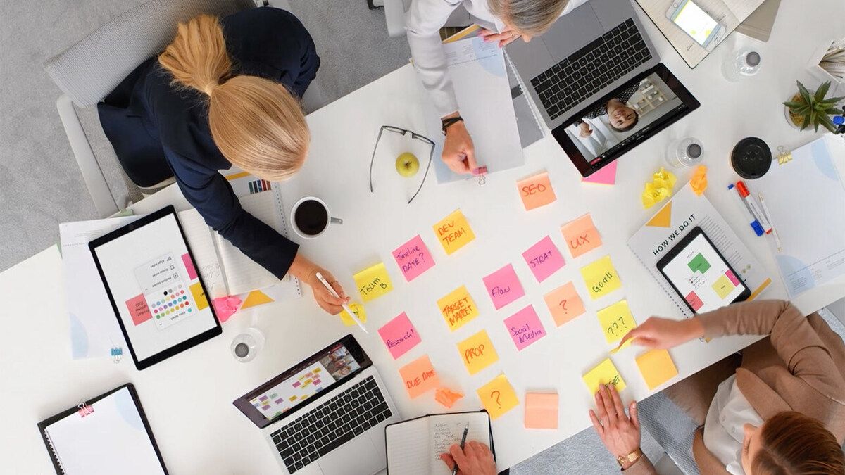 A bunch of sticky notes on the table with people reading them.