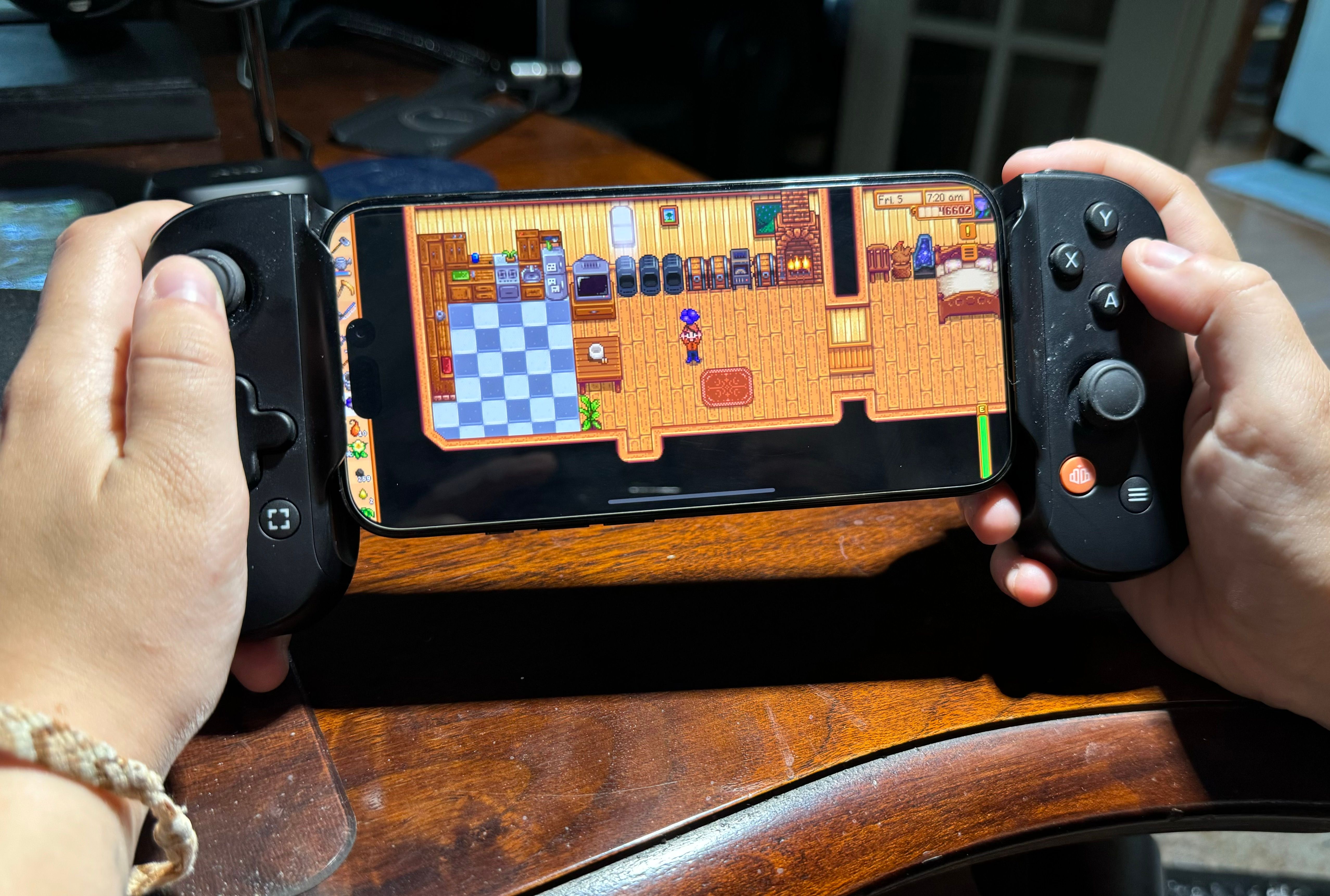 Person using Backbone One controller to play Stardew Valley on iPhone.