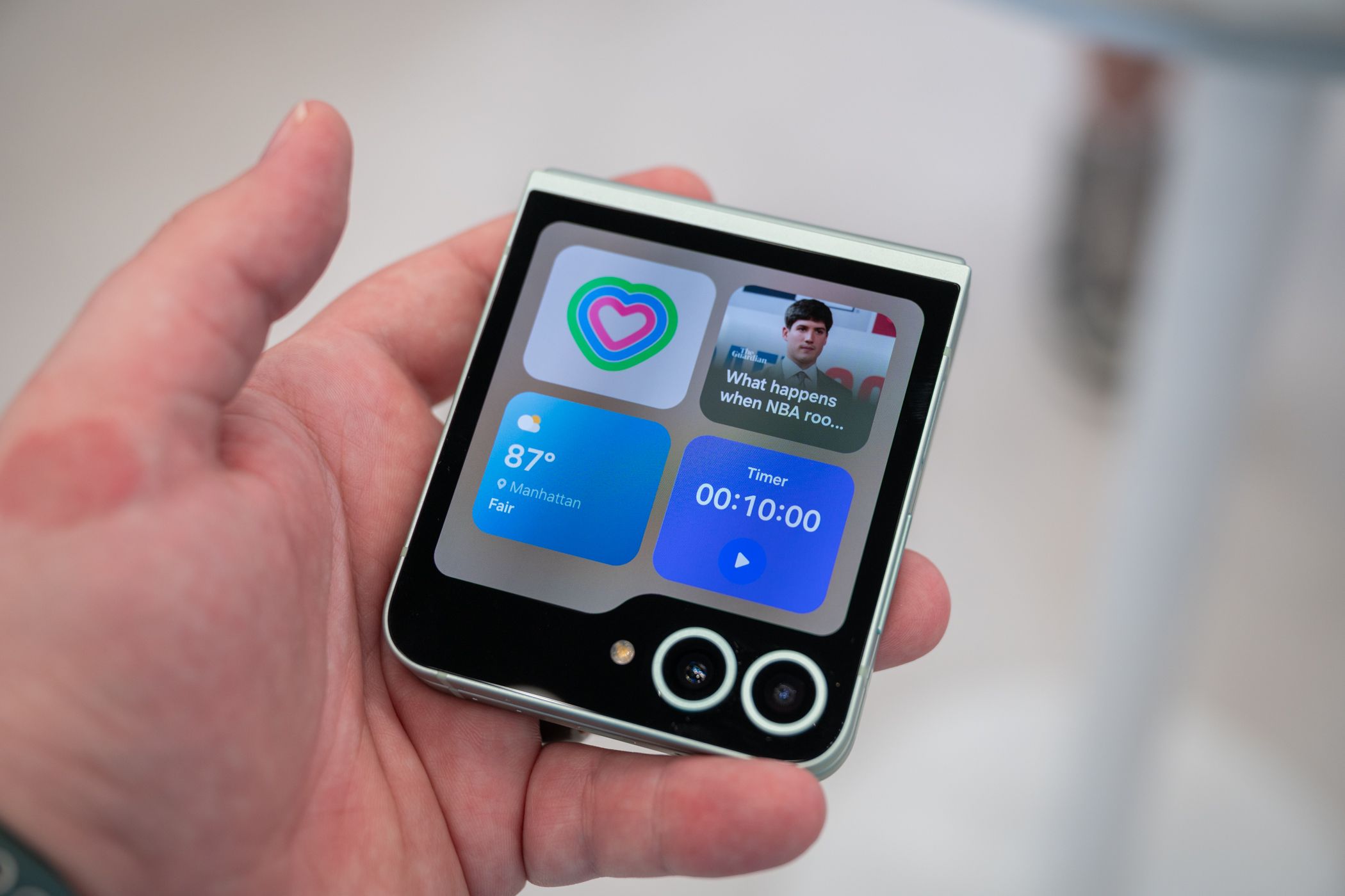 Person holding the samsung galaxy z flip 6 showing the cover display widgets.