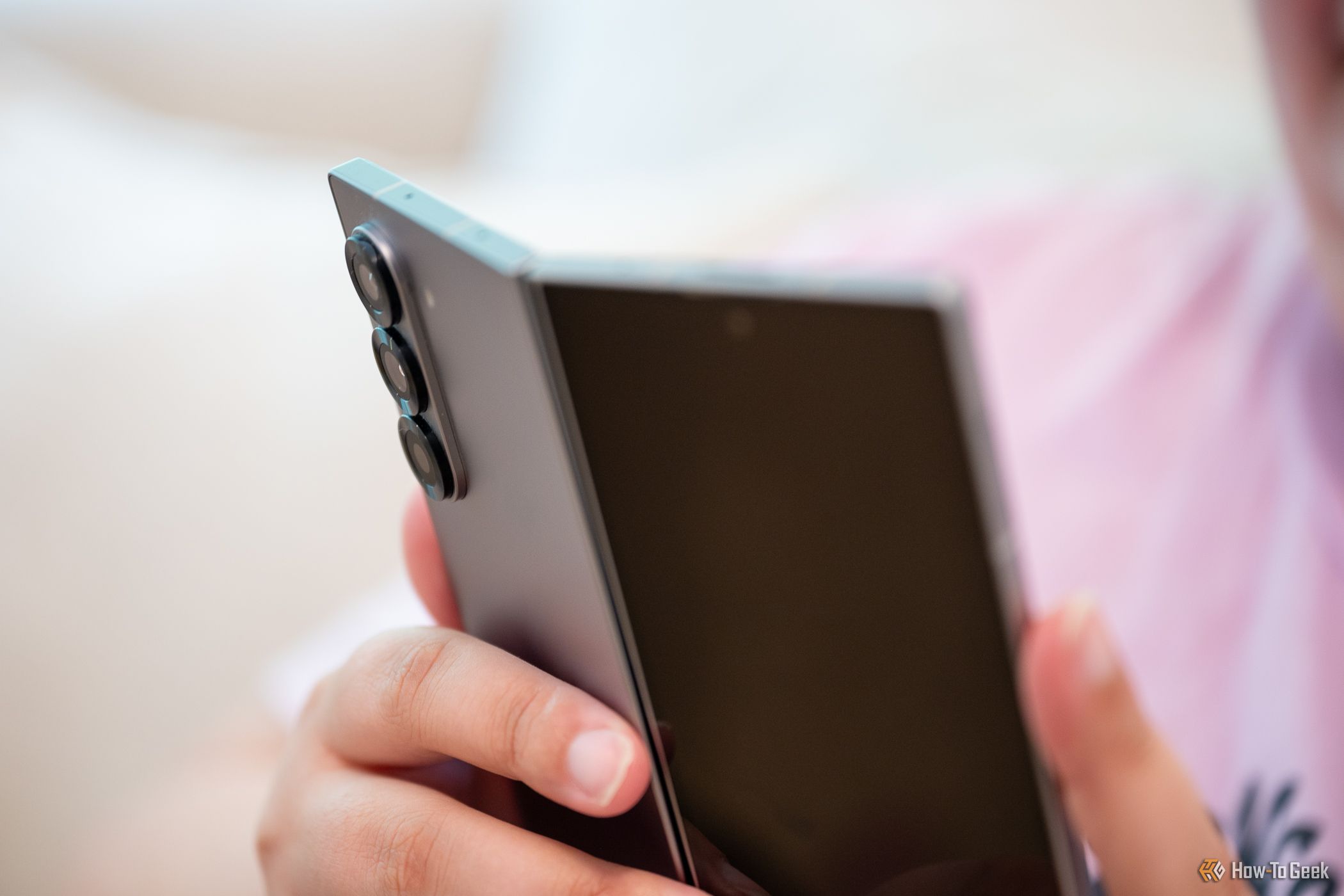 Person holding the Samsung Galaxy Z Fold 6 slightly bent open looking at the rear cameras