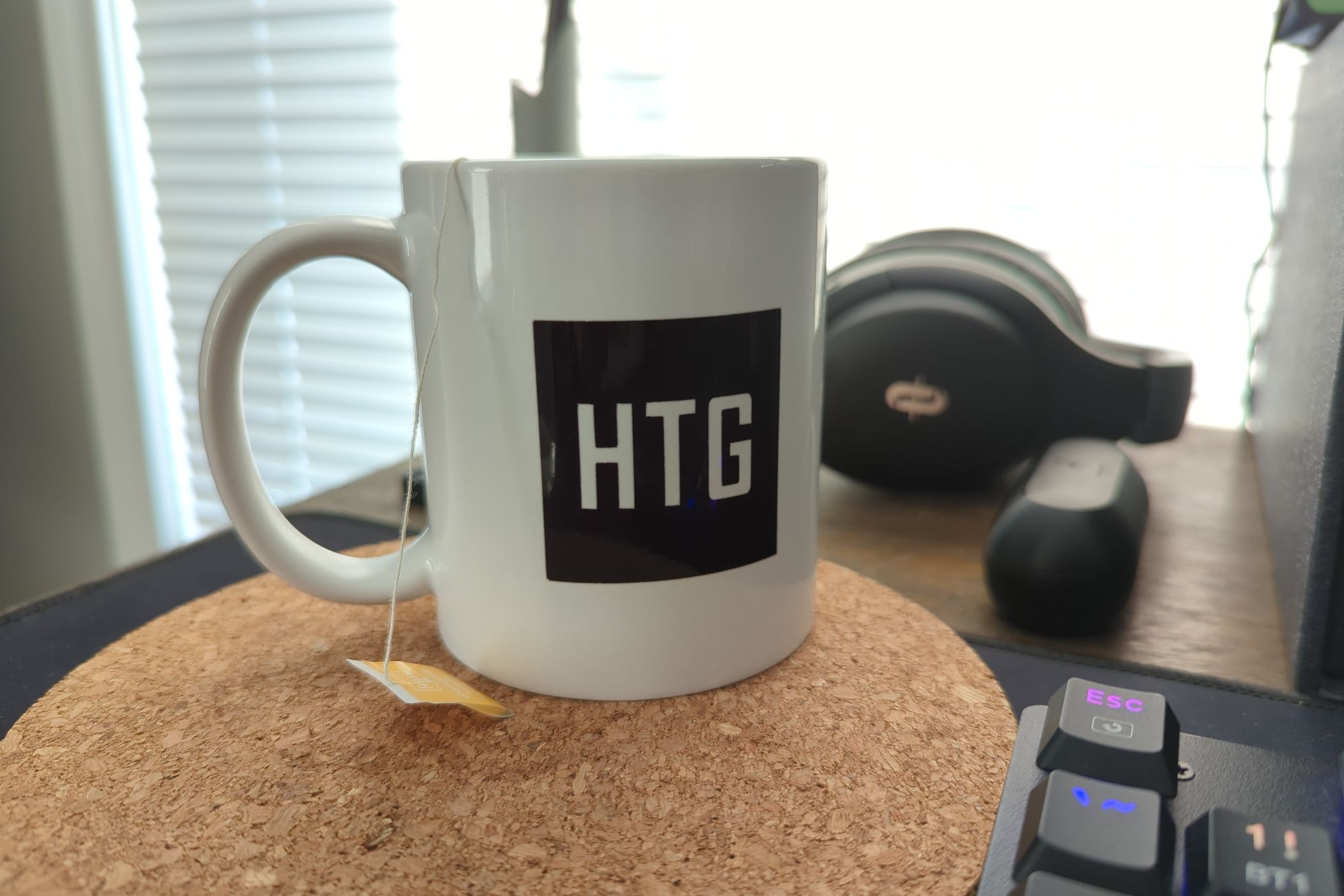 A white coffee mug on a desk with a tea string and tag hanging over the side.