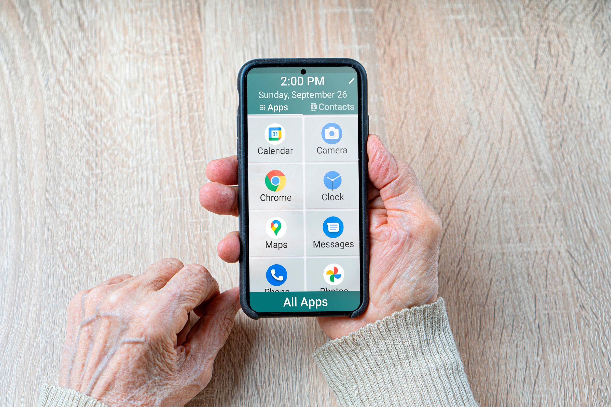 Wrinkled hands of an old woman holding a smartphone with a simple UI.