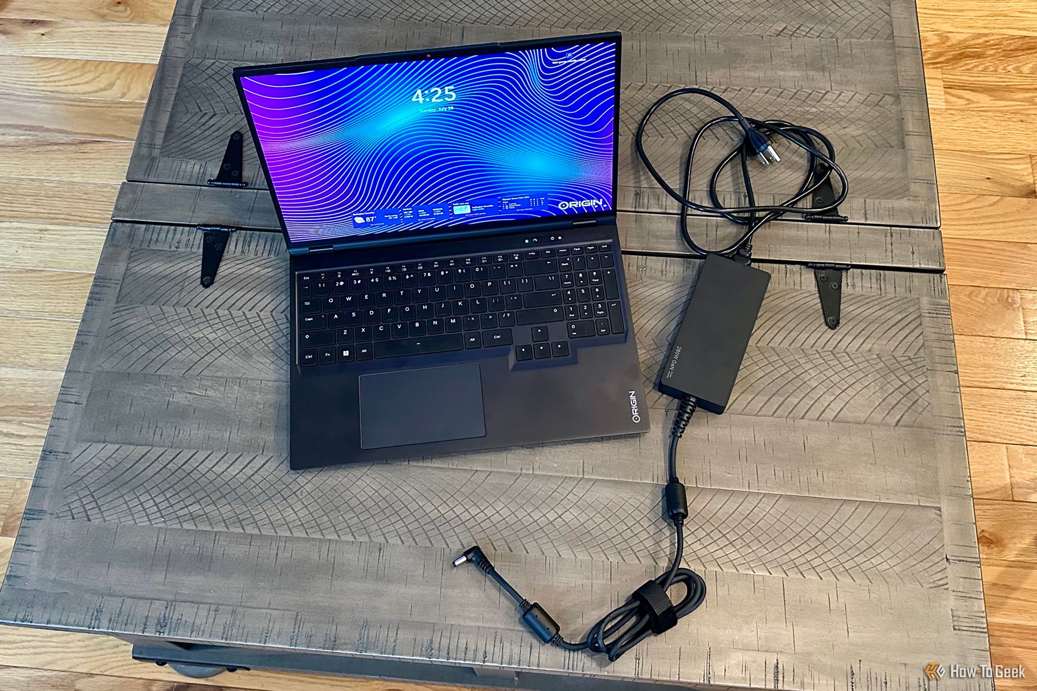 Origin PC EON16-X Laptop open on a table top next to its AC adapter