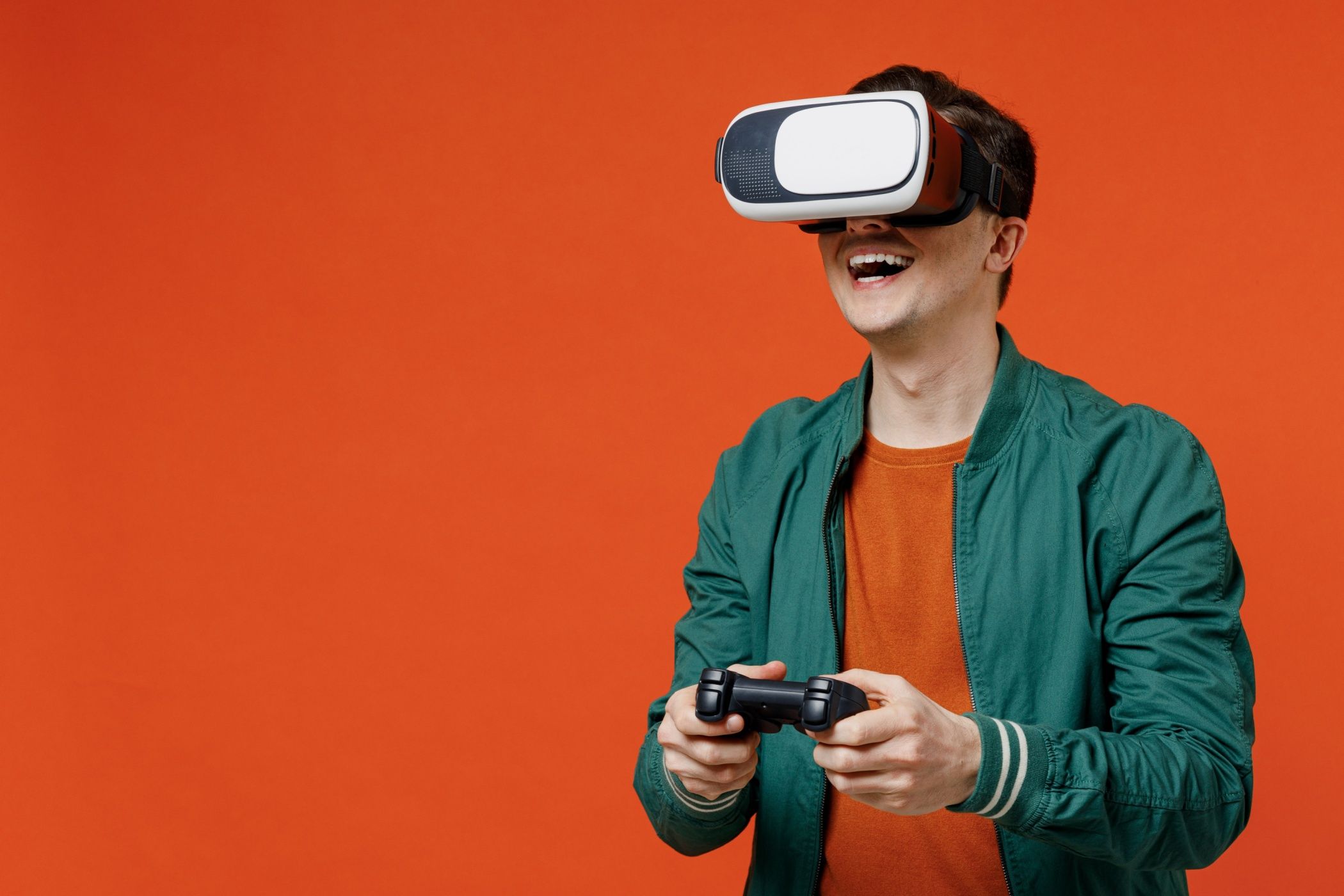 A man wearing a VR headset holding a game controller, smiling.