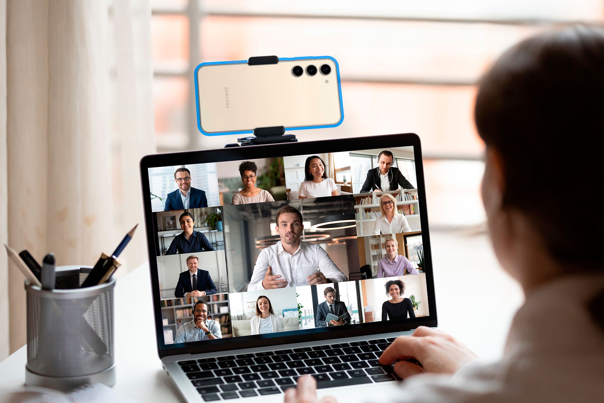 Woman in a meeting on a laptop using a phone as a webcam.