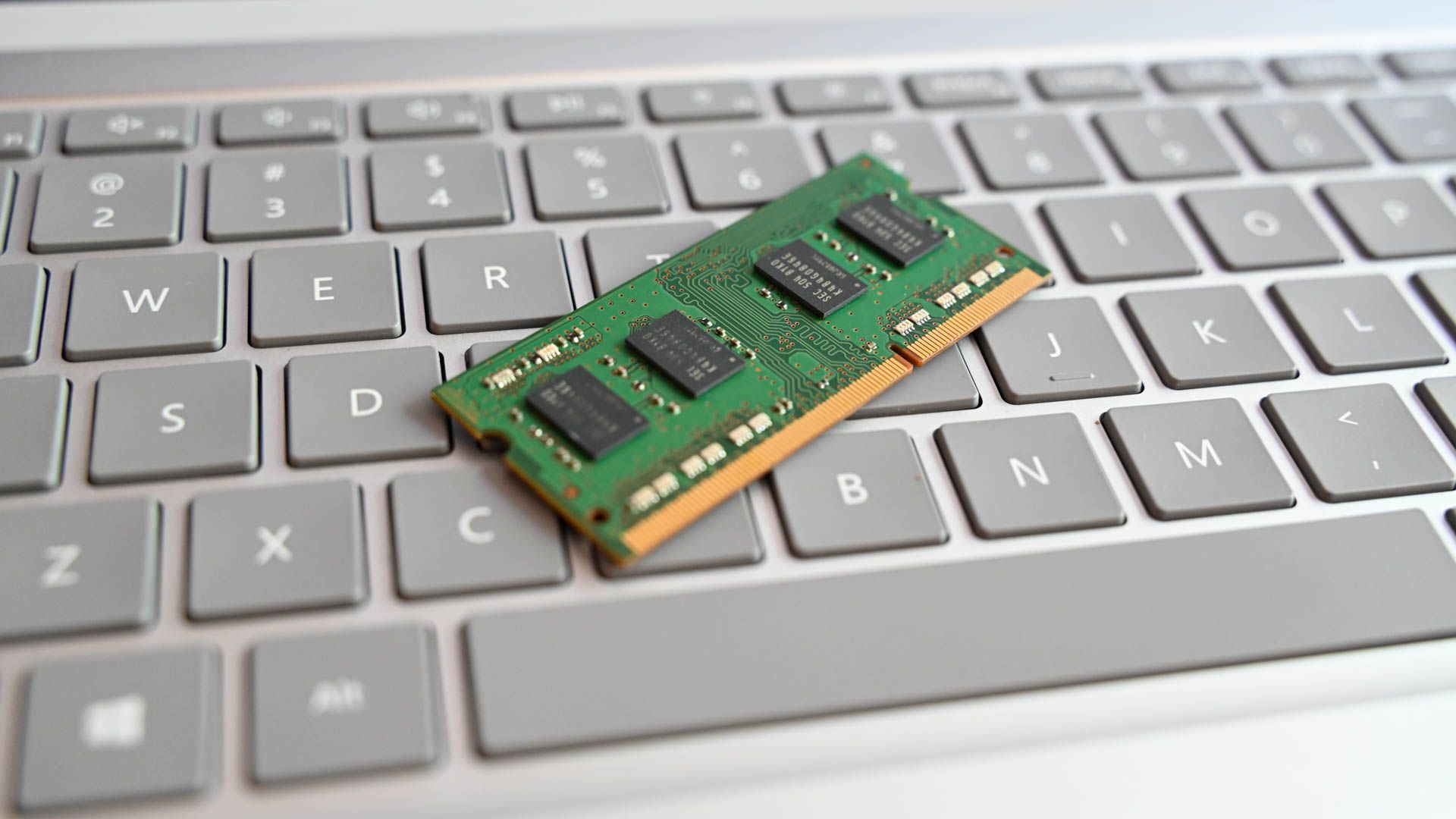 A laptop RAM stick sitting on a laptop keyboard.