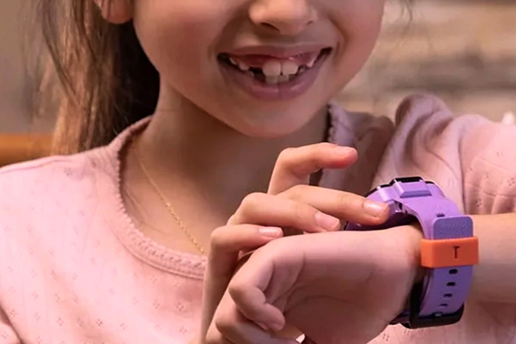 A little girl looking at the TickTalk 5 smartwatch on her wrist.