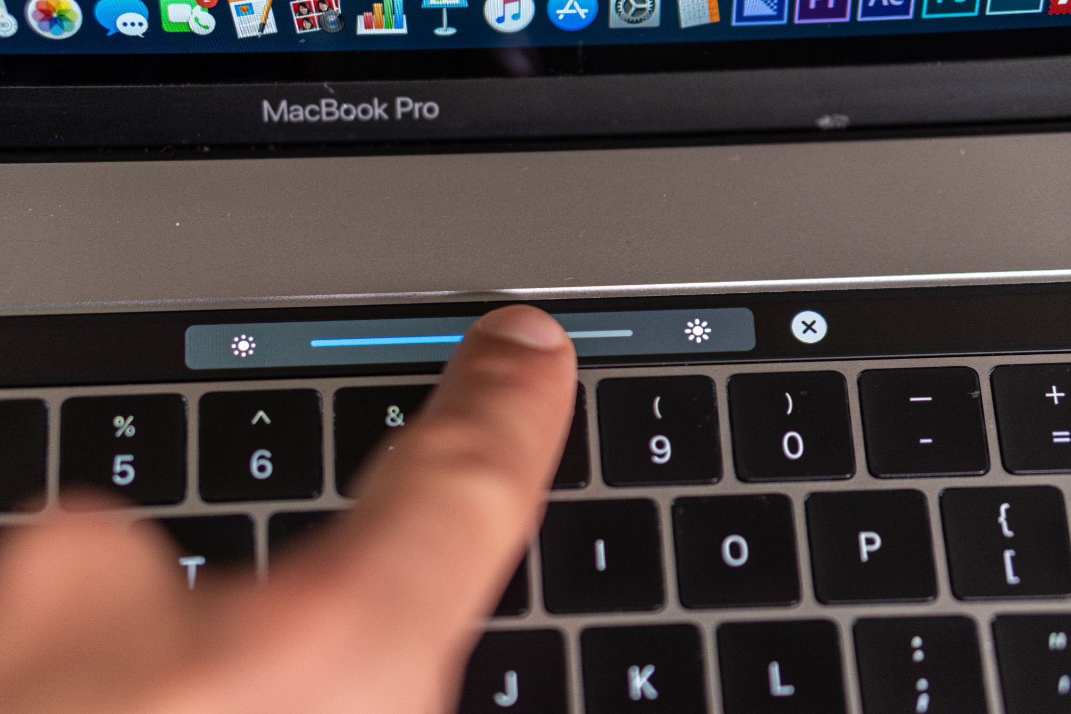 A MacBook Pro with Touch Bar adjusting the screen brightness.