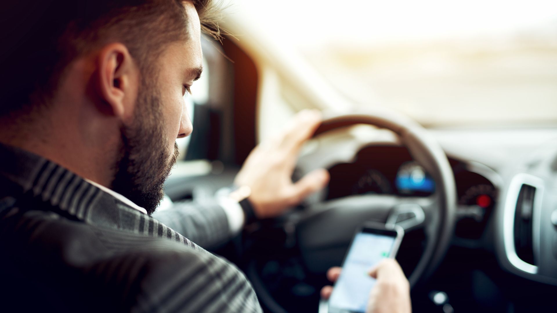 Man Looking At Mobile Phone While Driving A Car