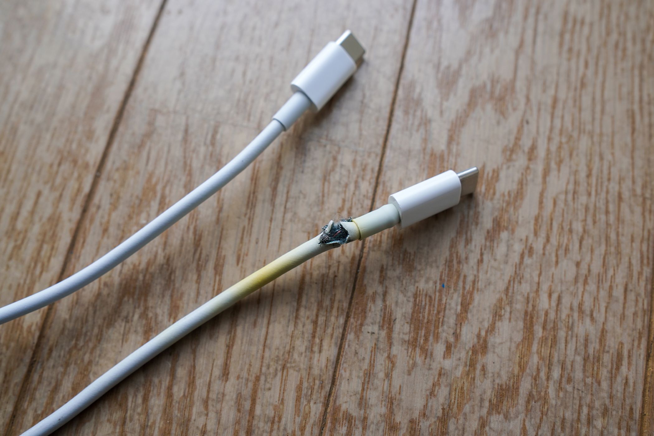 A frayed USB-C cable with scorch marks from electrical damage.