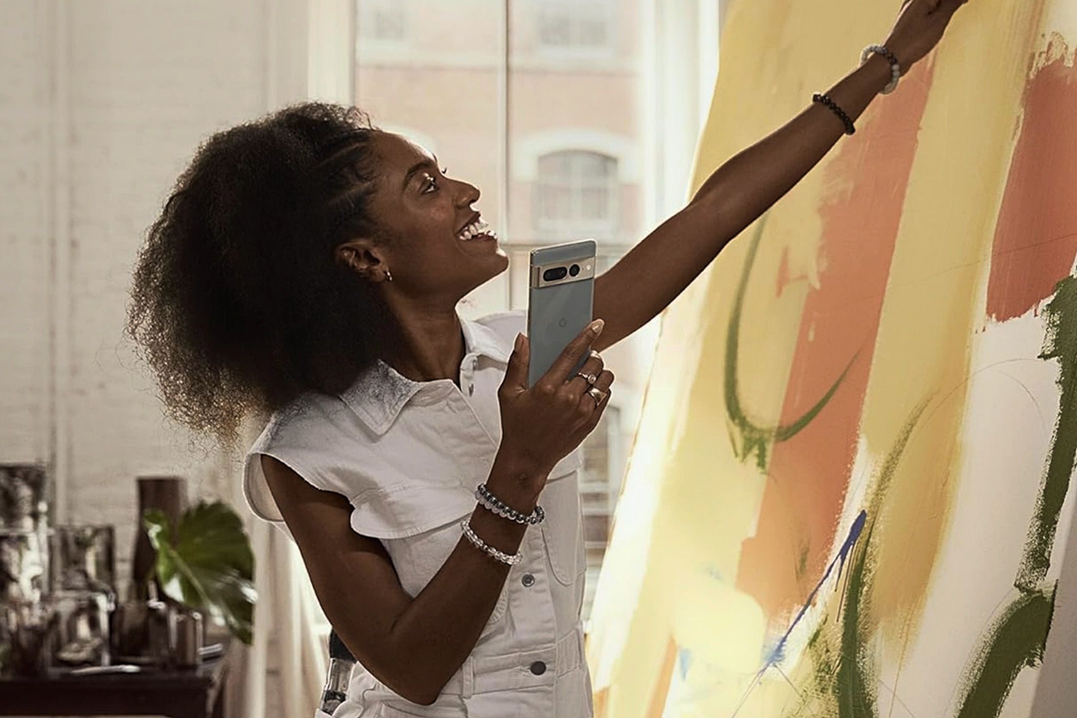 A woman painting while holding a Google Pixel 7 Pro.