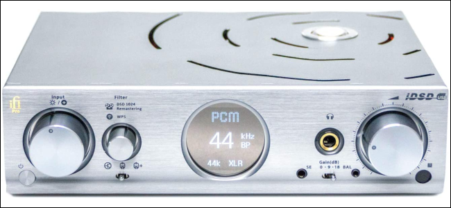 An external DAC with silver chassis and circular LCD display.