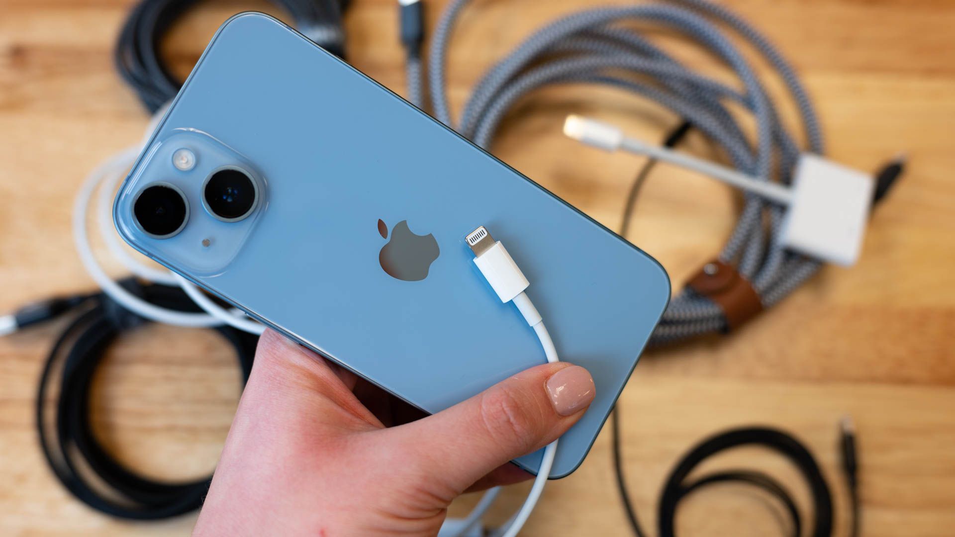 A blue iPhone with a selection of Lightning cables and accessories.