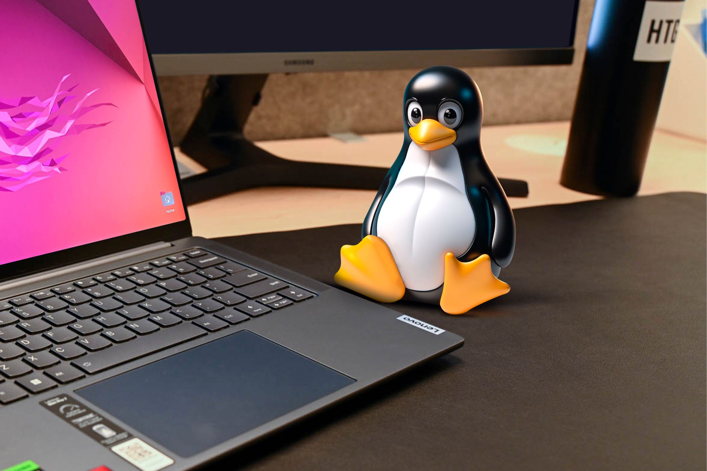 Linux mascot on a desk next to a laptop.