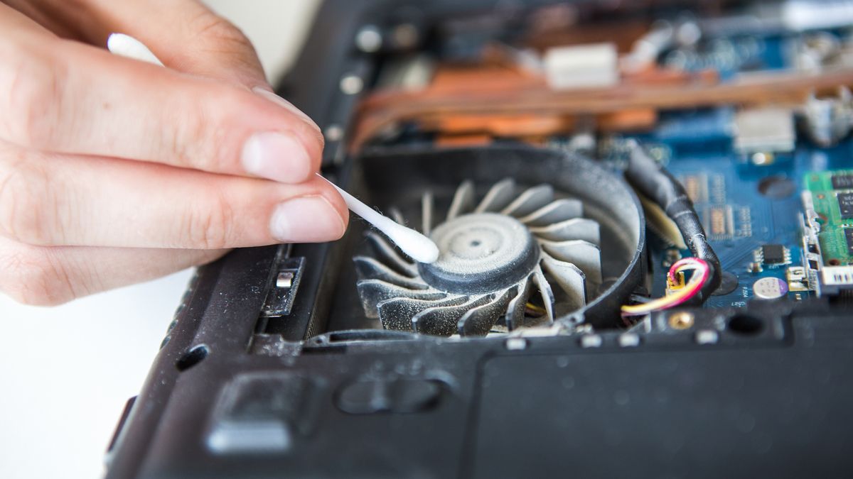 Person cleaning dust out of a laptop using a Q-Tip