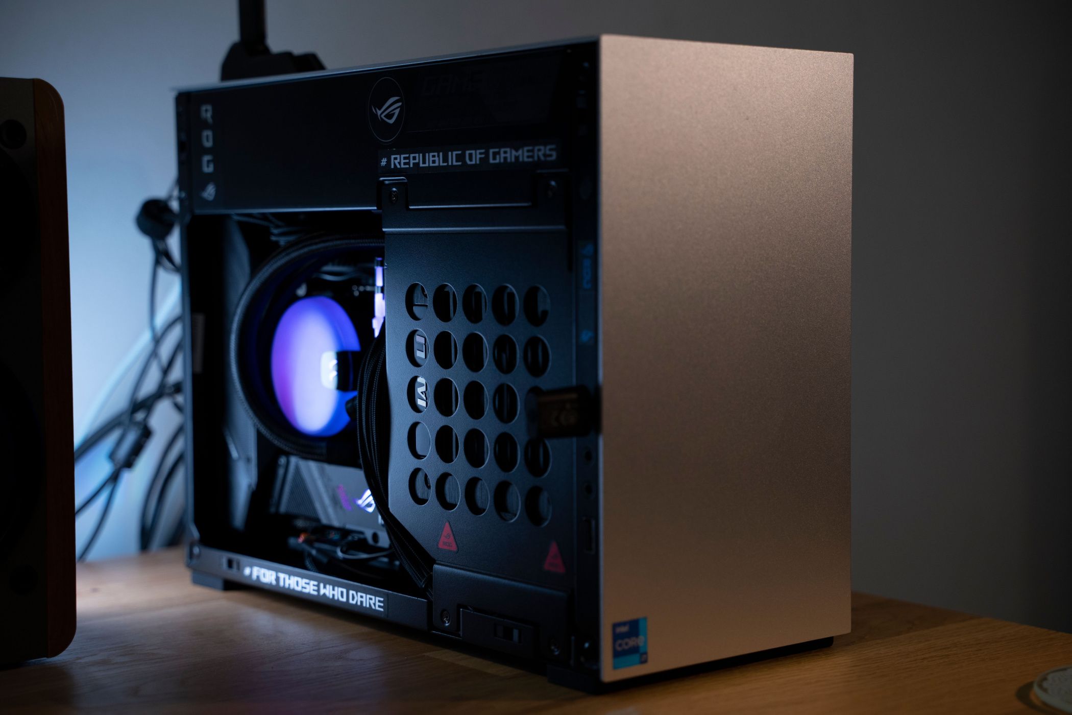 A tiny gaming computer sitting on a wooden table with a gray background.