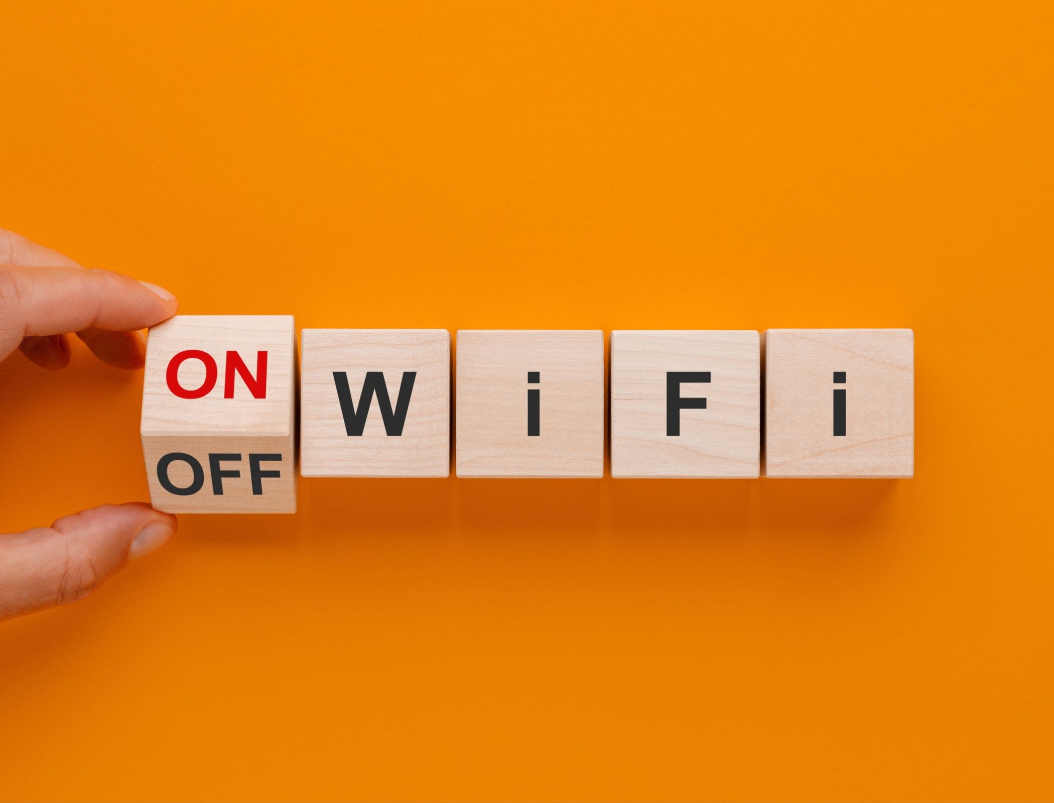 A hand flipping a Wi-Fi sign made of wooden blocks to the on position.