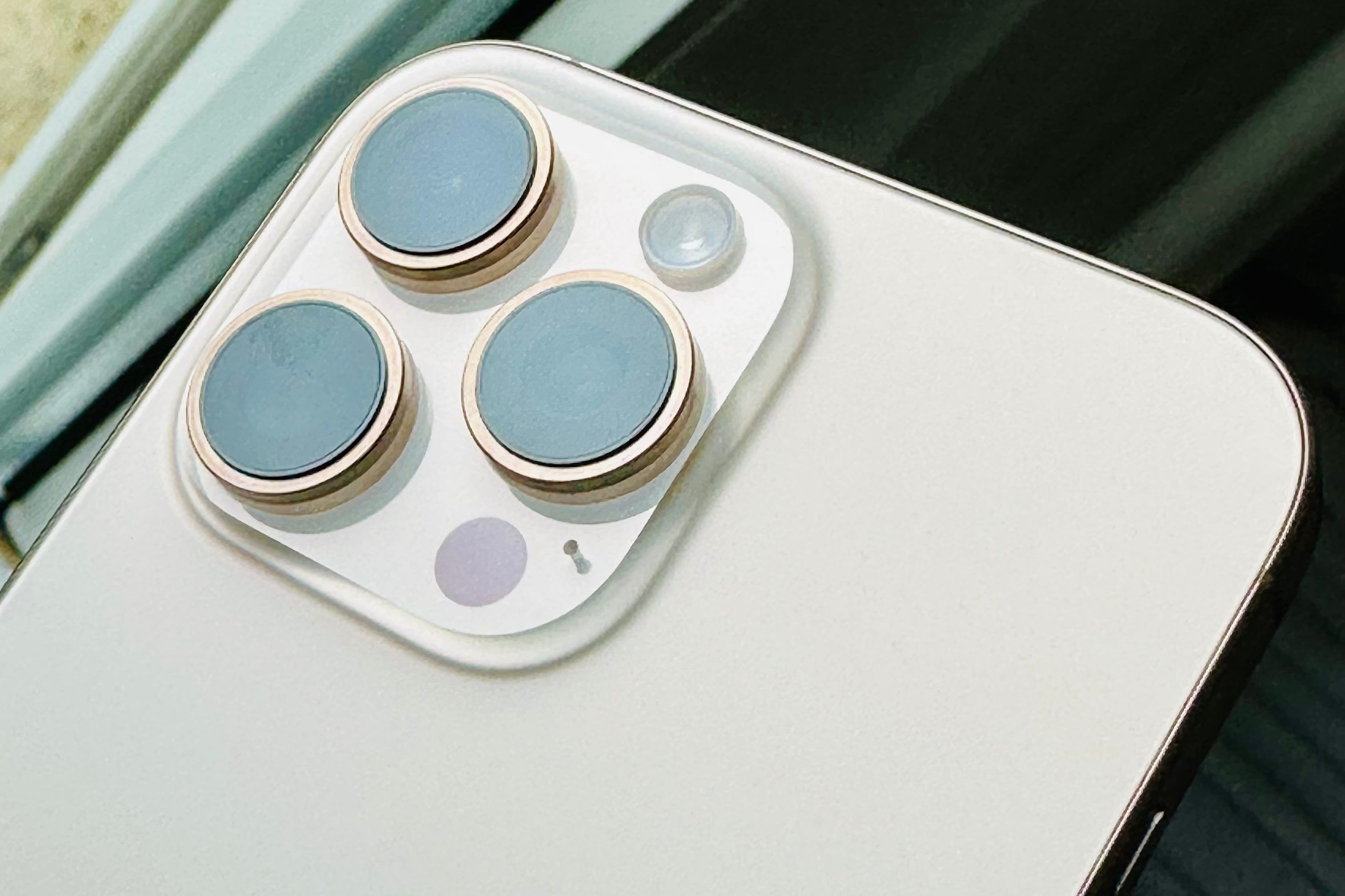 Closeup of the back cameras on an iPhone 16 Pro Max in the Desert Titanium color finish.