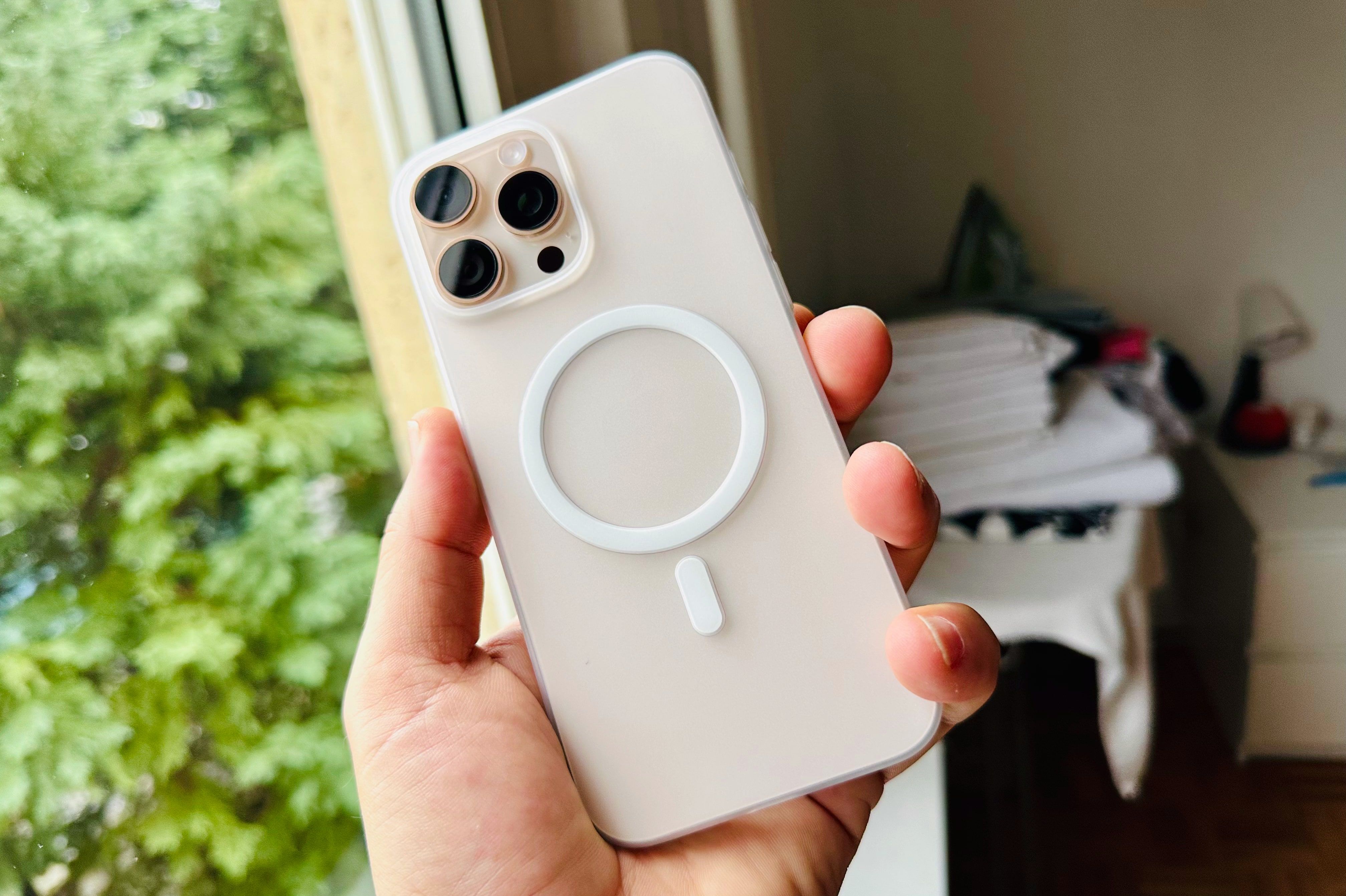 Hand holding an iPhone 16 Pro Max in a Totallee MagSafe clear case, showcasing the backside with three cameras.