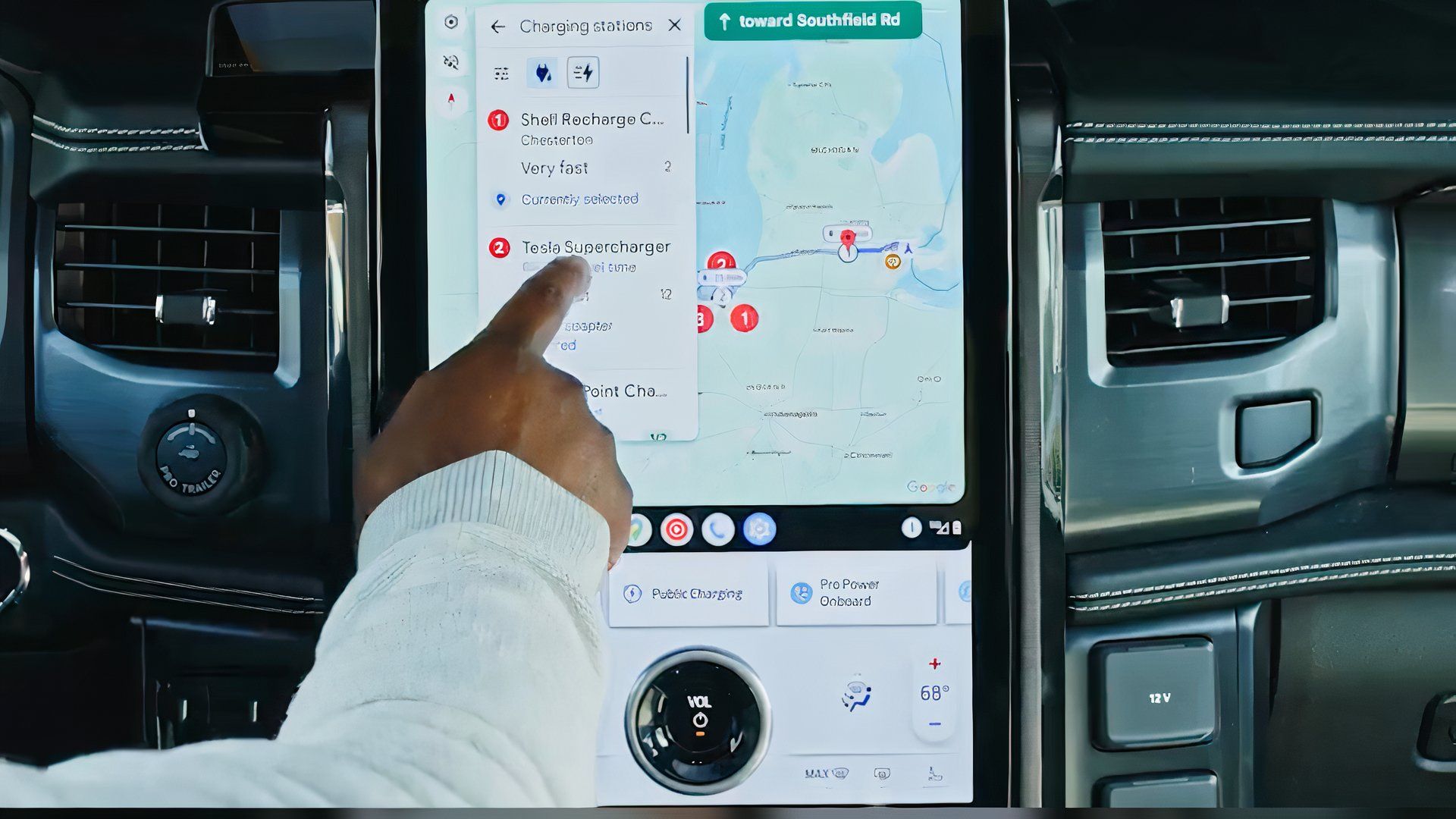 Hand selecting a Tesla Supercharger in Google Maps in a Ford electric vehicle.