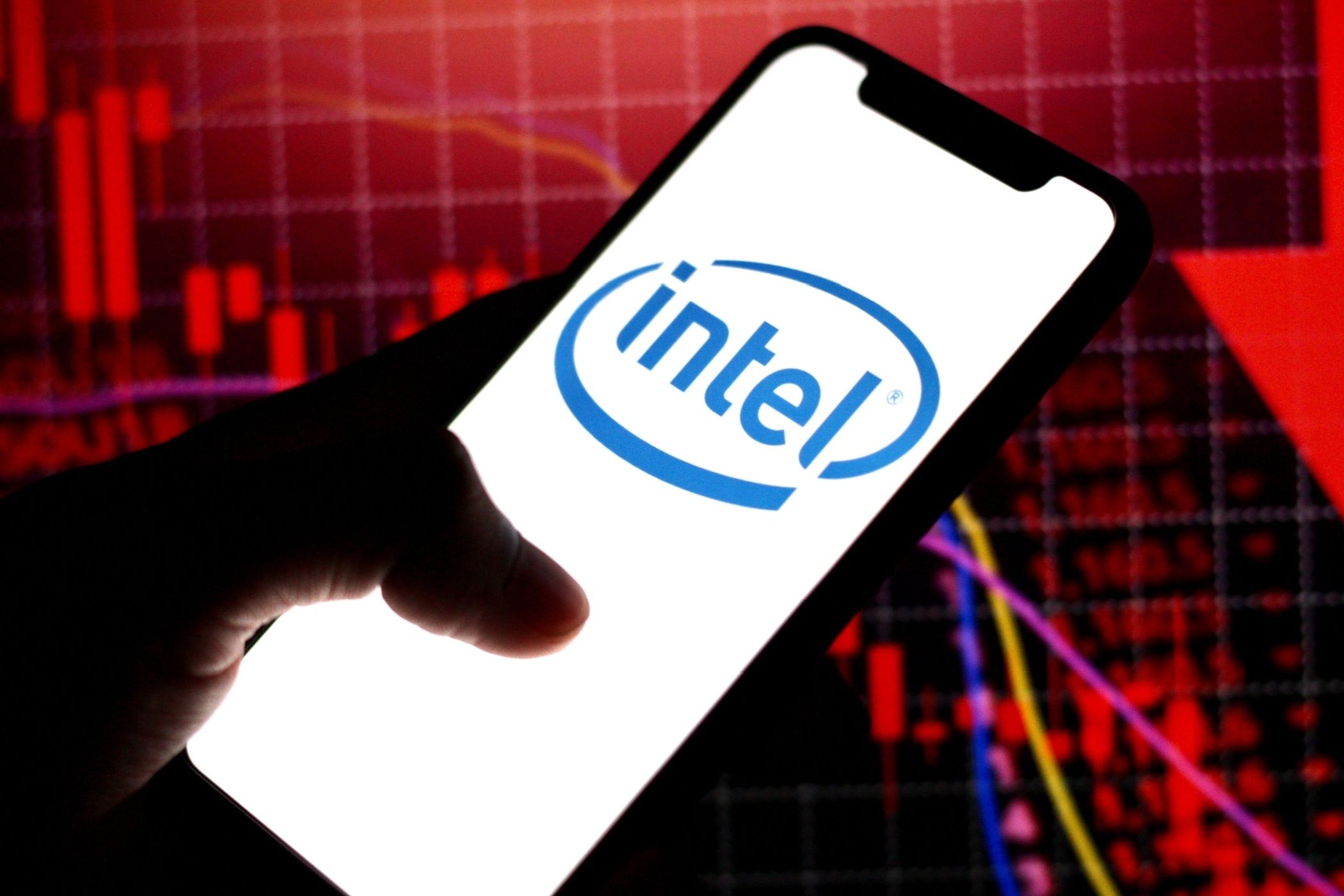 In this photo illustration,the logo of Intel,is displayed on a smartphone withstock market declines in the background