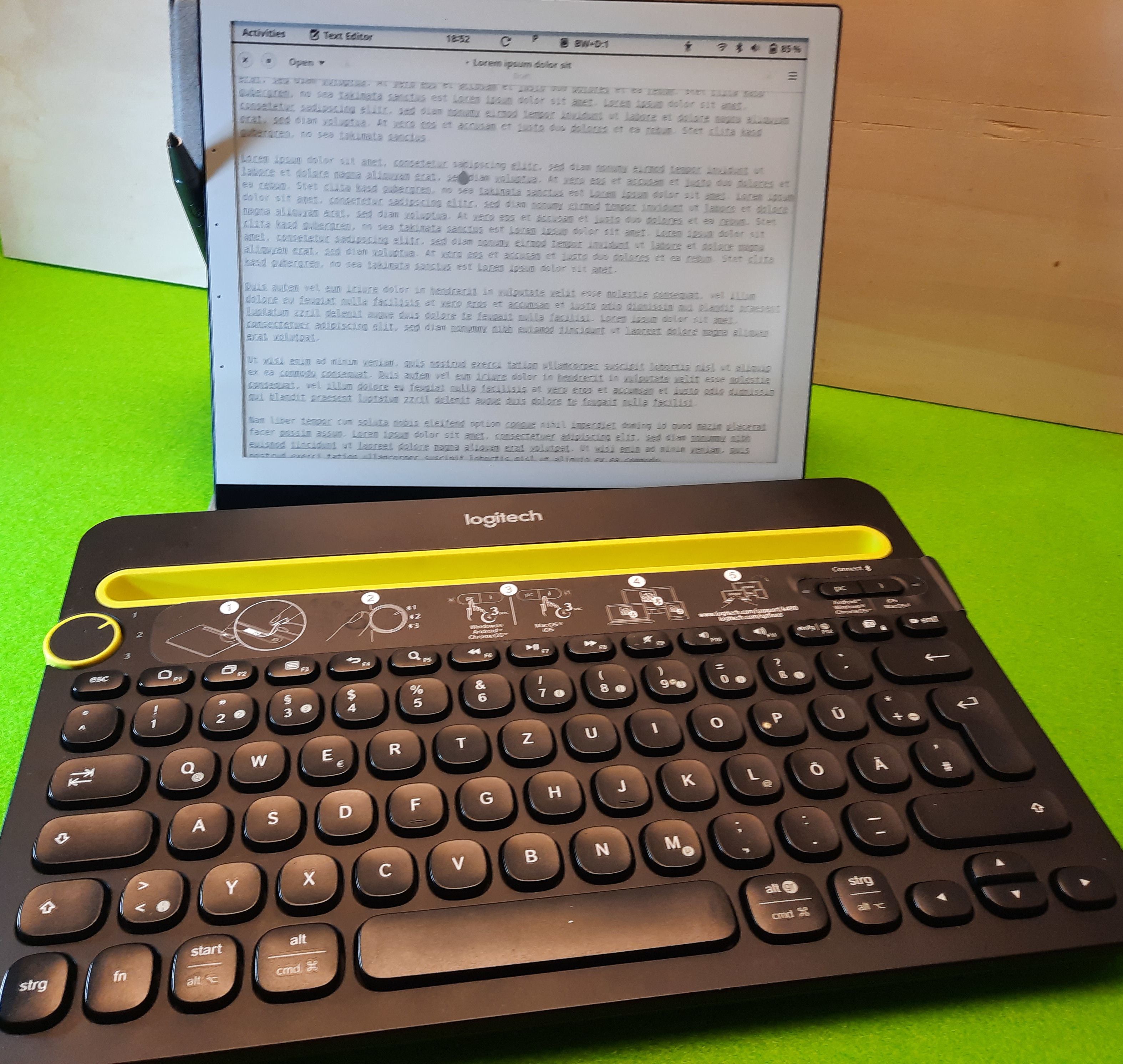 A Logitech keyboard in front of a PineNote tablet displaying text in an editor.