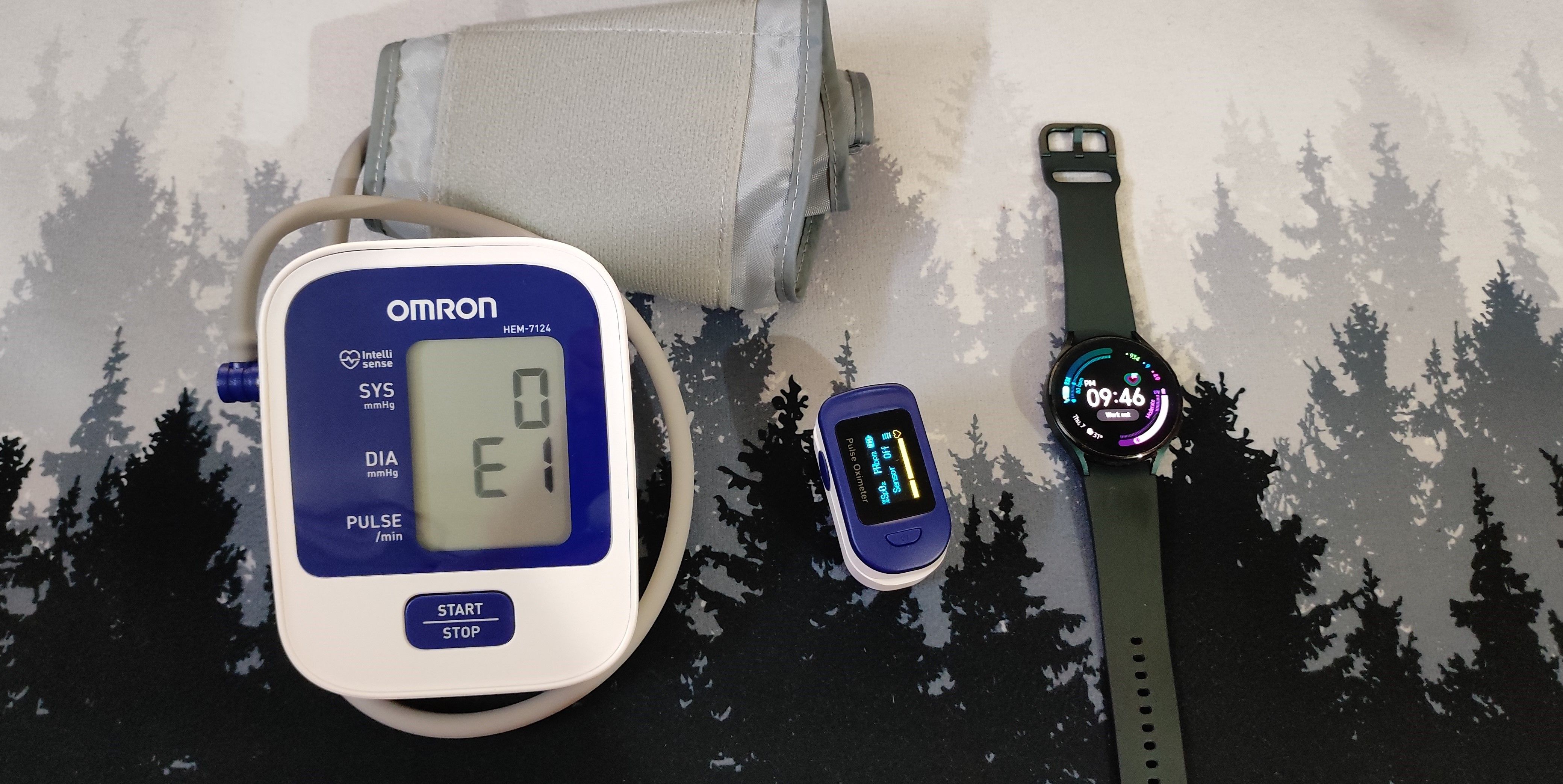 A galaxy watch 4, Pulse Oximeter, and Blood Pressure Monitor Side by Side.