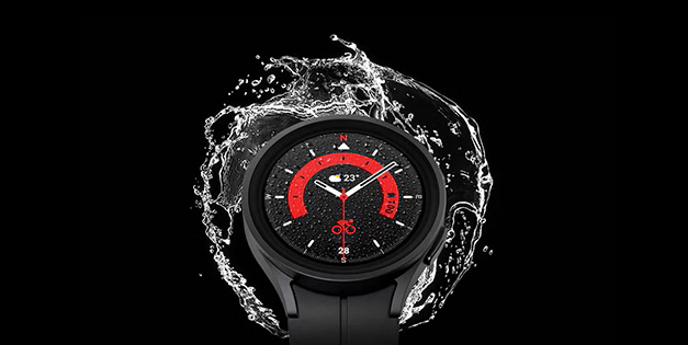 A Galaxy Watch with water splashing behind it on a black background.