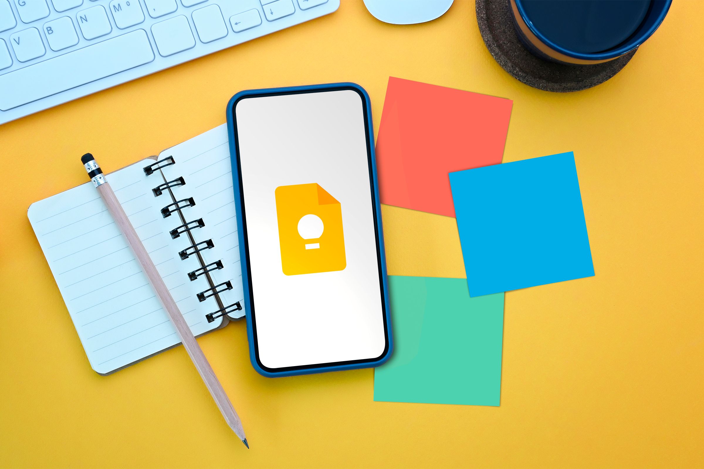 A phone above a notebook with the Google Keep logo and some sticky notes beside it.