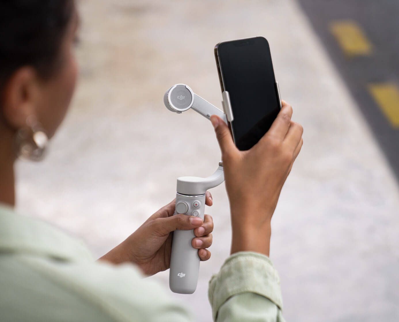 A woman about to attach her phone to the DJI OM 5.