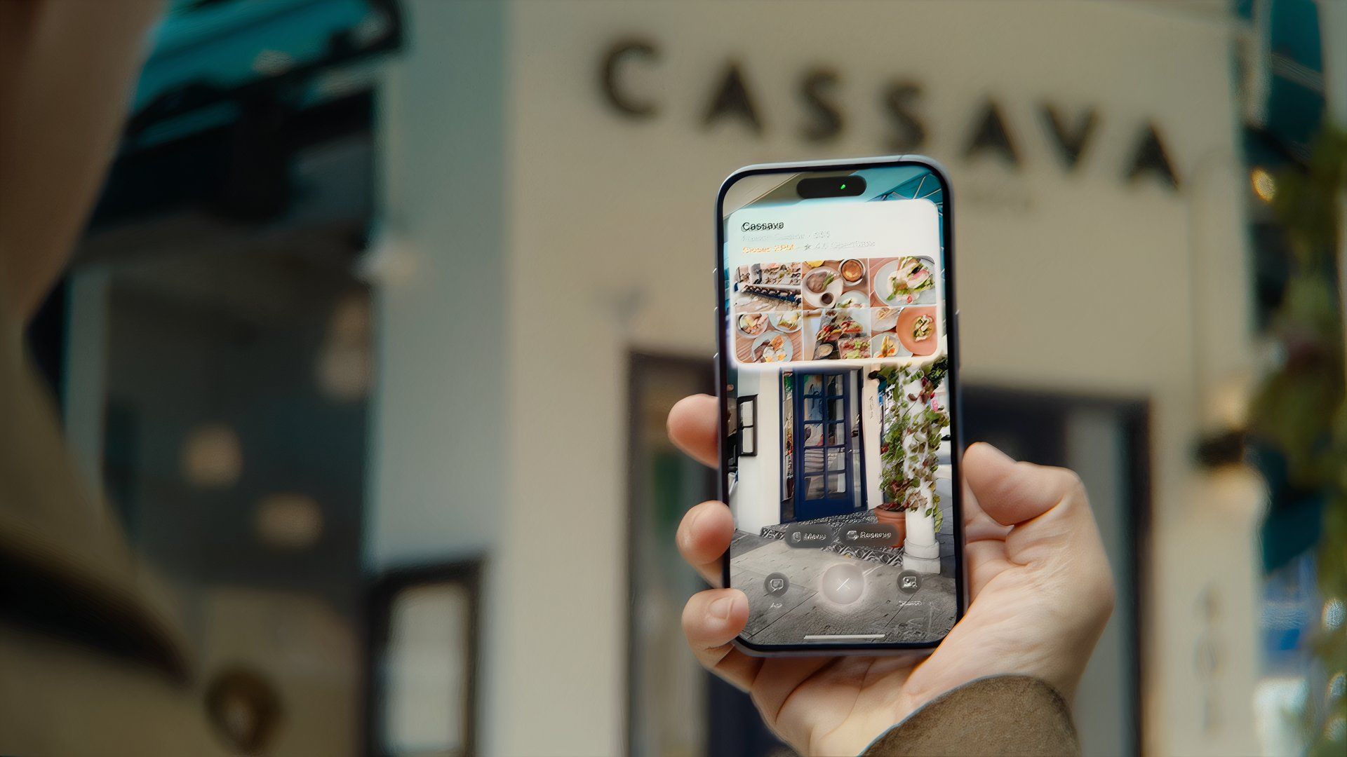 Hand holding an iPhone, with visual intelligence in the Camera app showing information about a restaurant.