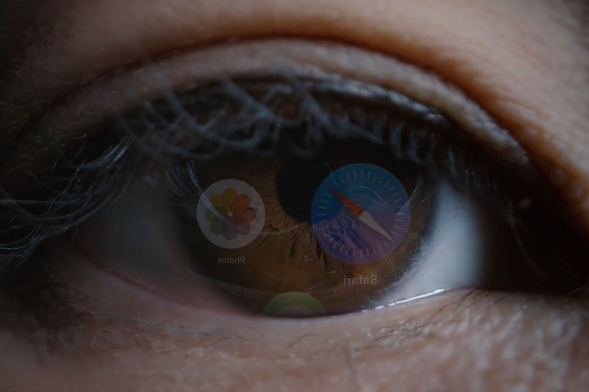 Human eye macro with reflections of the Safari, Photos and Messages app icons on the retina.