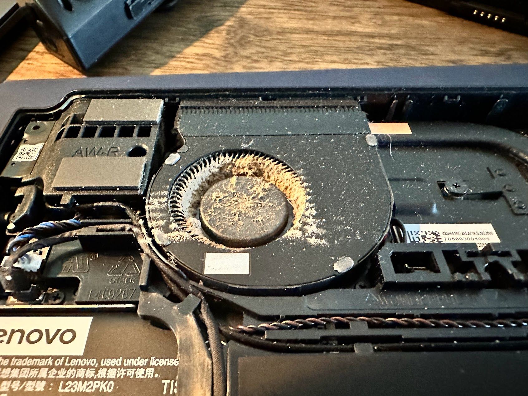 Lenovo Legion Go with back plate removed, showing heavy dust inside the cooling fan up close.