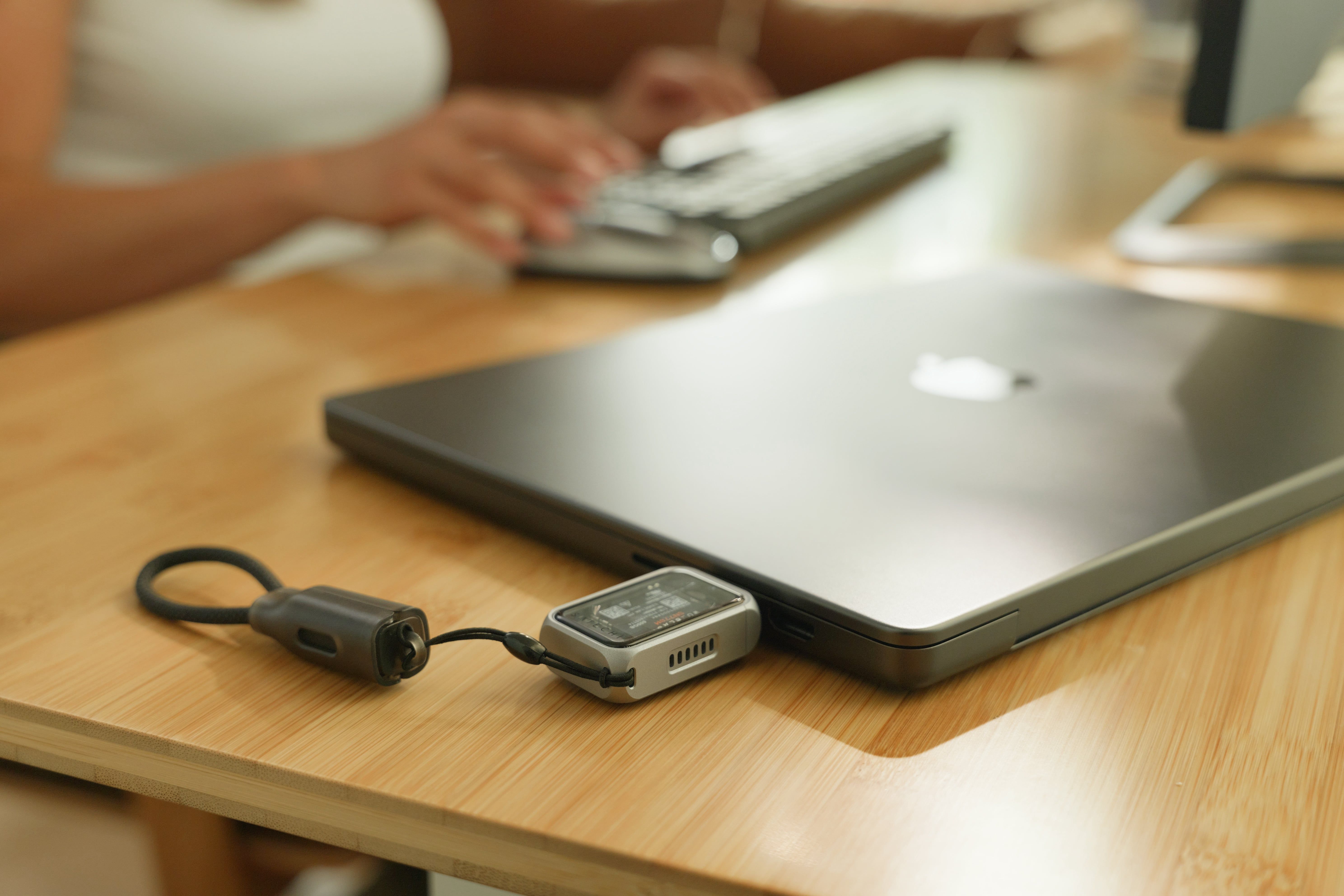 Satechi's SSD enclosure plugged into a MacBook Pro lying on a wooden desk.