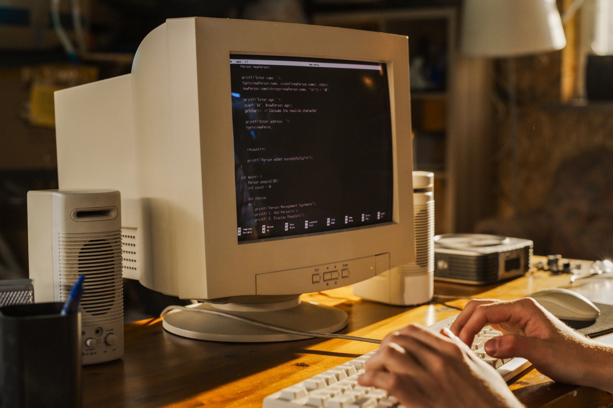 Person's hands at the keyboard of a retro computer with a beige plastic contstruction.